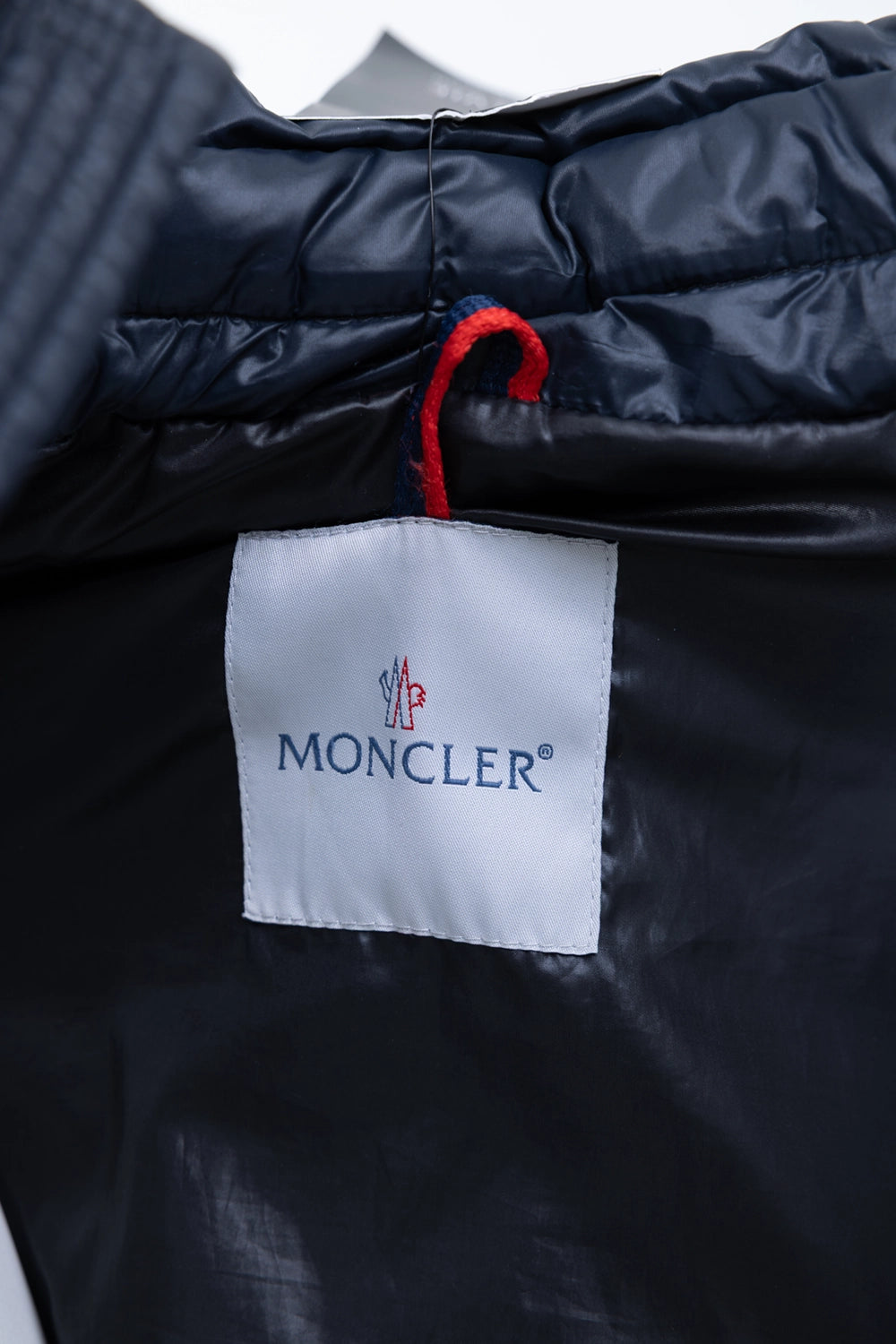 Pre-owned Moncler men's down jacket in navy, interior label view, woven logo tag with tricolor hanger loop