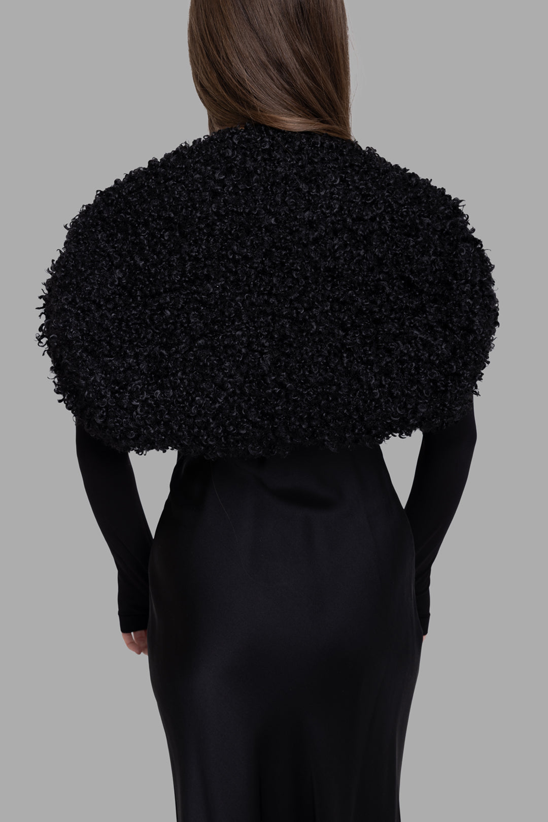 Norma Kamali women's black faux fur long sleeve shrug, back view, voluminous curly texture across shoulders.