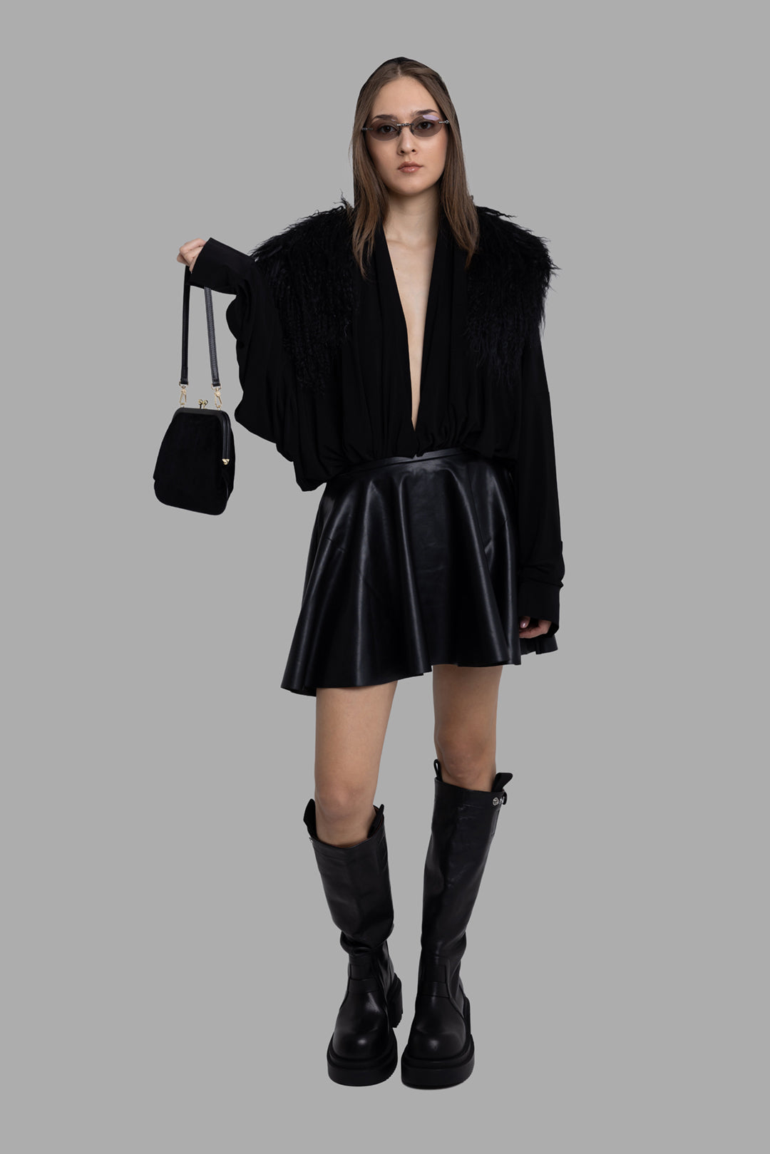 Norma Kamali women's black flared vegan leather mini skirt, on-model full length, fluid A-line silhouette.