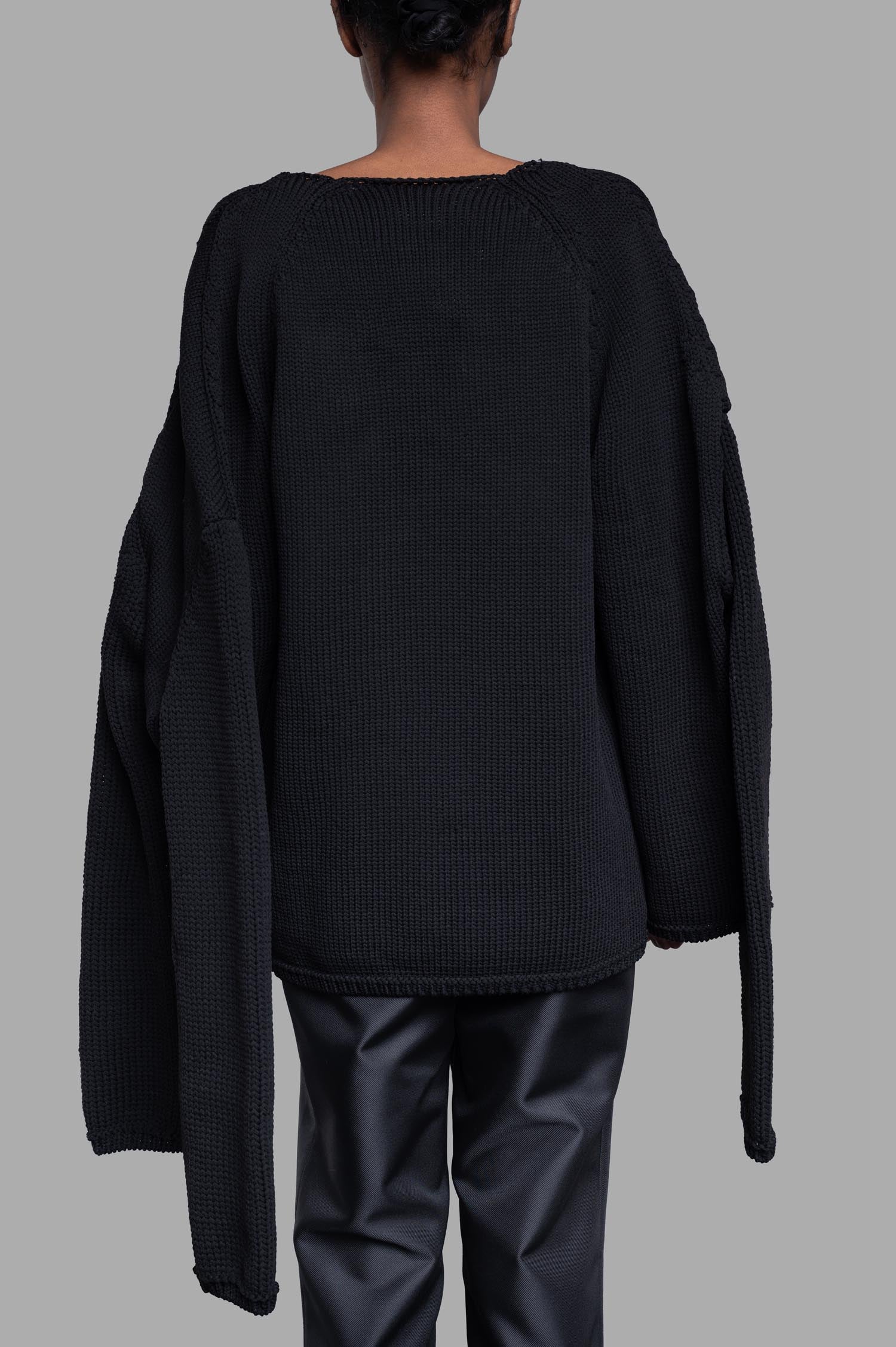 Model showcases the Comme des Garçons Multi-sleeve Sweater in black, emphasizing its innovative sleeve structure from the.