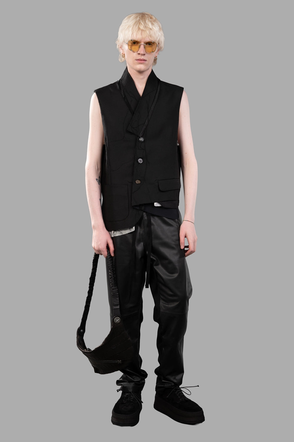 Full-length view of black asymmetric vest with shawl collar and flap pockets