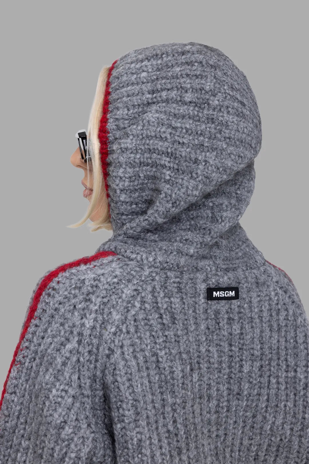 MSGM women's grey hooded knit zip cardigan, side view of hood, close-up of black MSGM logo patch and red contrast trim.