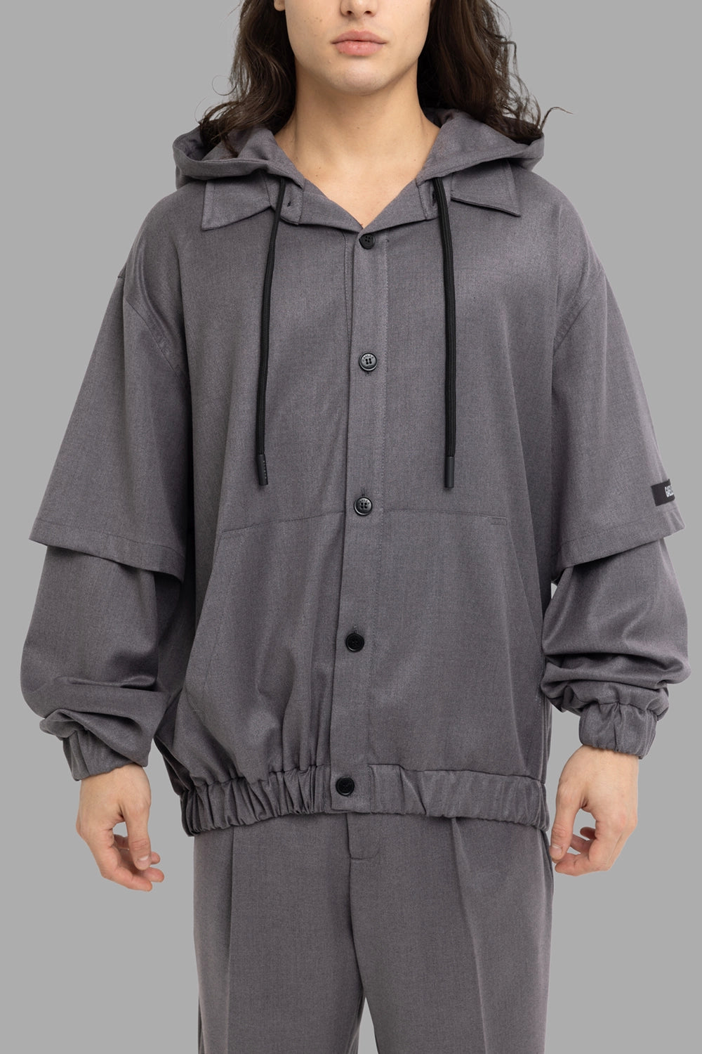 Gaëlle Paris men's hooded overshirt in black, front view, double-layer sleeves, elastic cuffs, button front