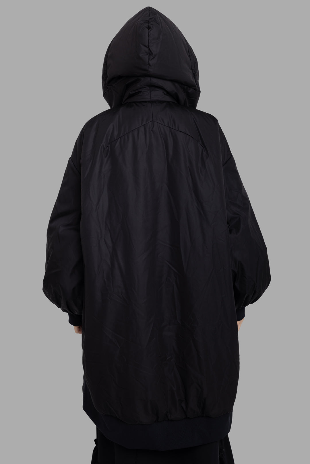 Sehnsucht Atelier women's black hooded puffer coat, back view, rounded cocoon shape with gathered hem and voluminous sleeves.