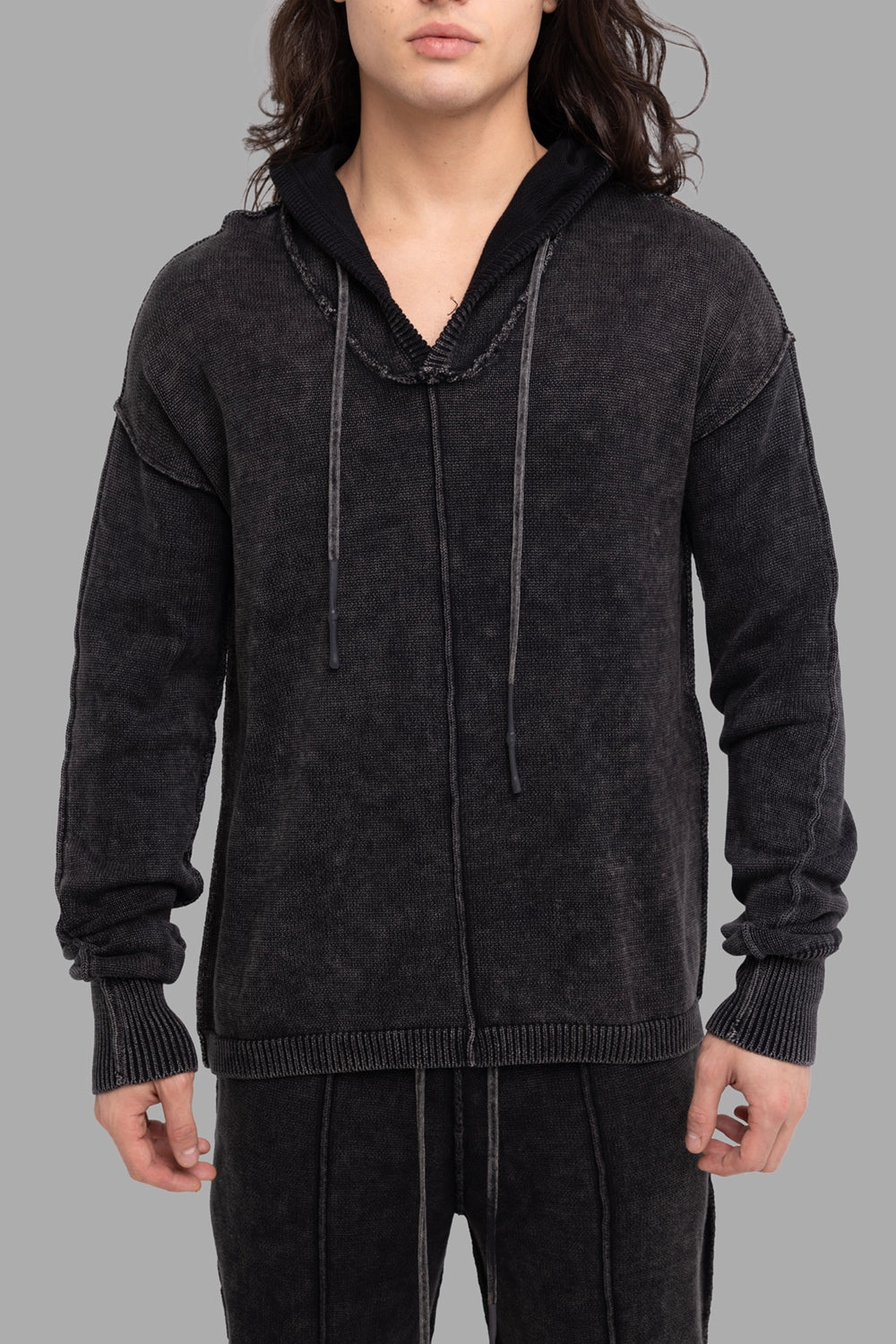 Justin Gall men’s knit hoodie in black, front view, raw-edge hood opening with long drawcords and ribbed hem