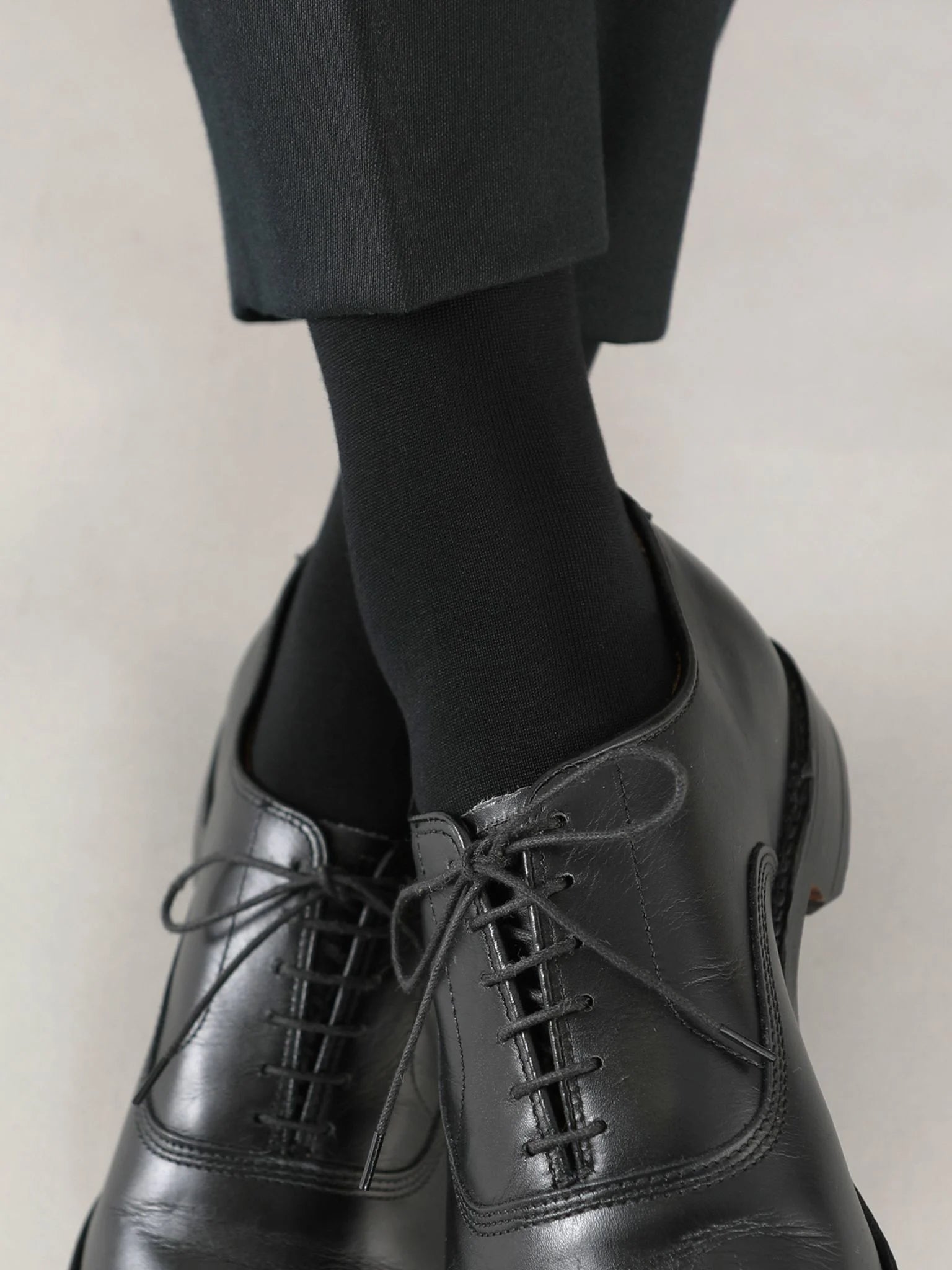 Tabio Supima Cotton Plain Mid-Calf Socks in black, showcased on-model with polished black shoes, feature a seamless flat toe.