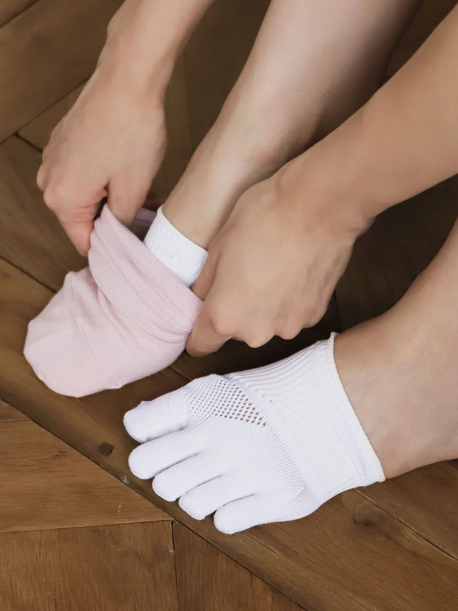 Tabio. Toe Cover For Hallux Valgus in white, featuring individual toe sections for comfort and support, shown being put on.