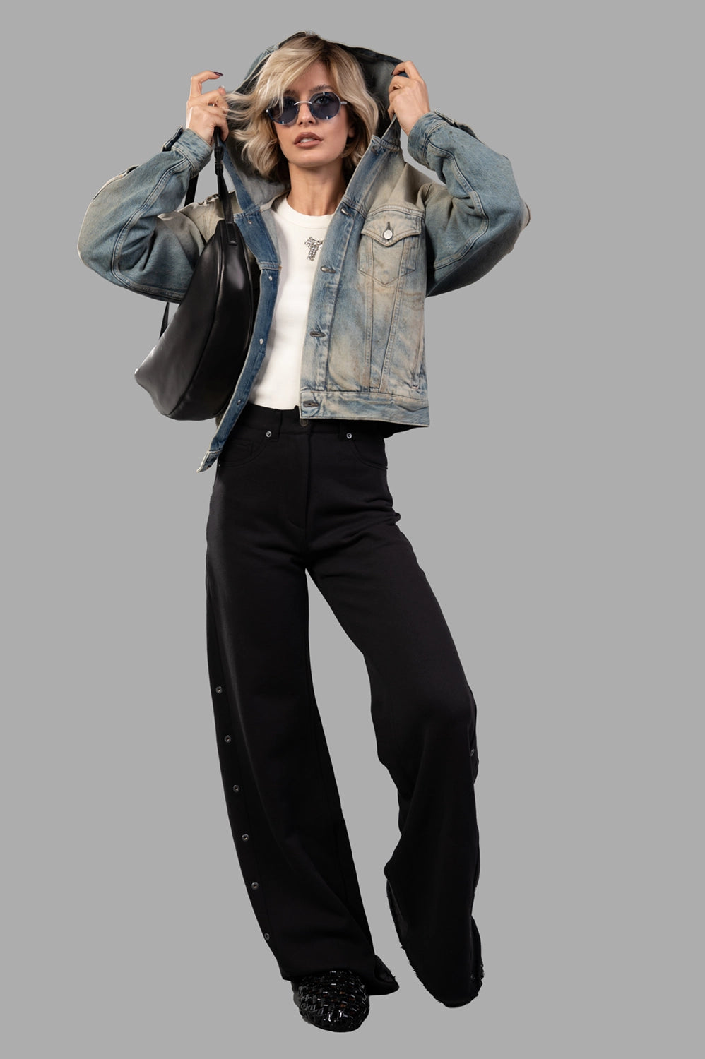 Full-length view of model wearing mid-blue hooded denim jacket with button front, fitted waist-length cut and worn-in wash