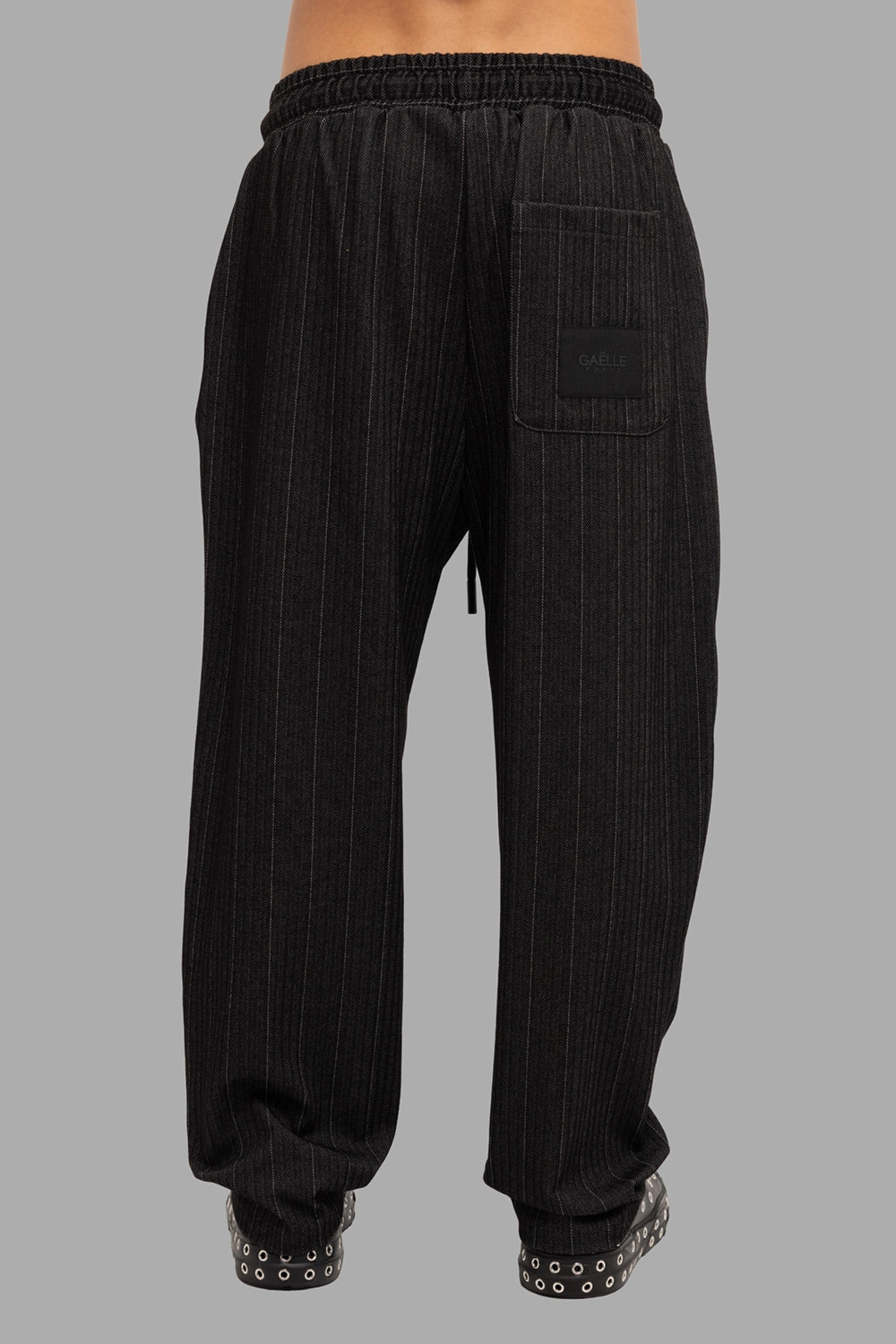 Gaelle Paris men’s jogger trousers in black pinstripe, back view, patch pocket with rubber logo label