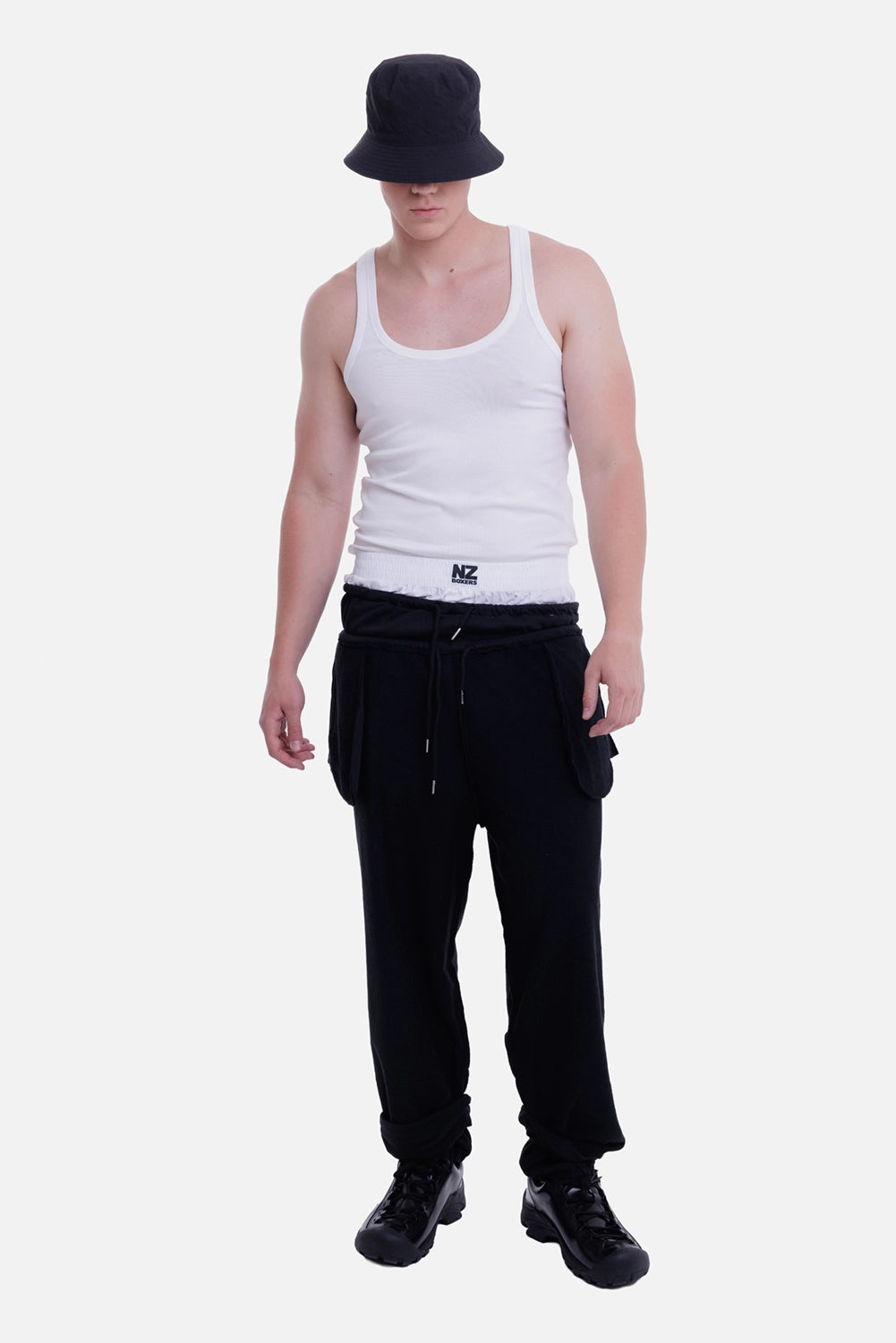 Natasha Zinko men's black joggers, full-length model view with white boxer waistband and pouch pockets