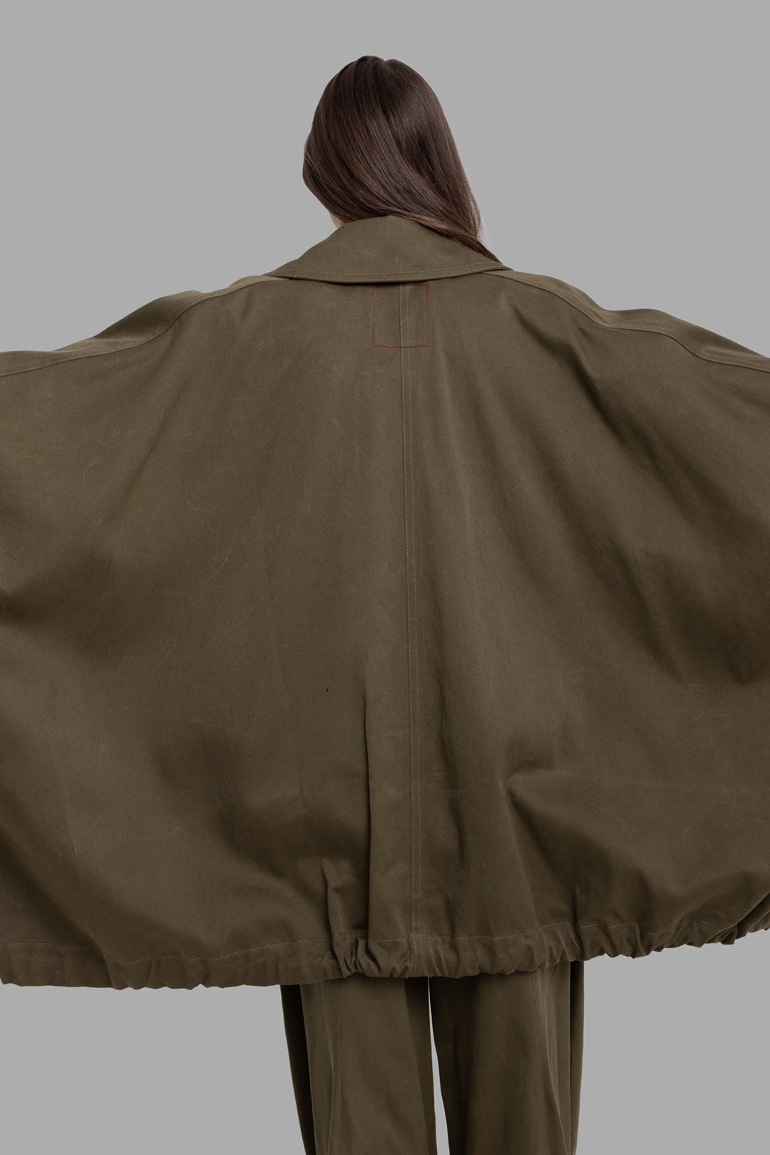 Uma Wang women's dark green Kew jacket, back extended view with arms outstretched showing dramatic winged volume and subtle red stitch detail