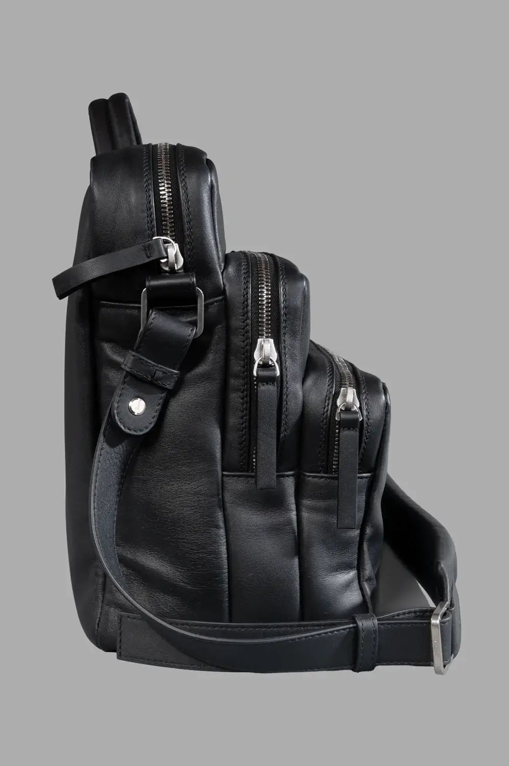 Marsèll laptop bag in black, side view, tiered profile with silver zips and strap