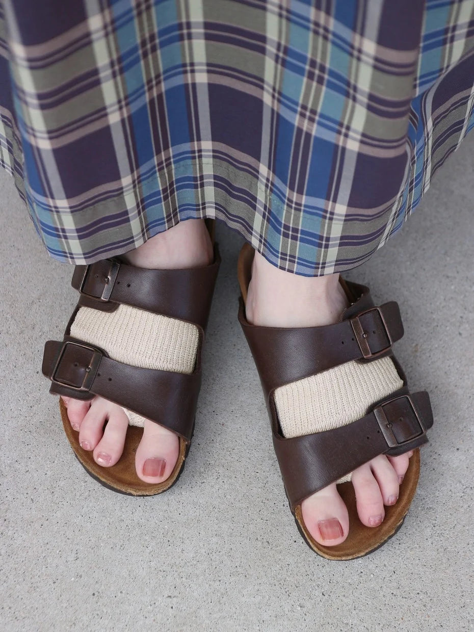 Tabio. Linen Plain Toe Band in black worn over brown sandals, showcasing a comfortable fit and stylish design detail.
