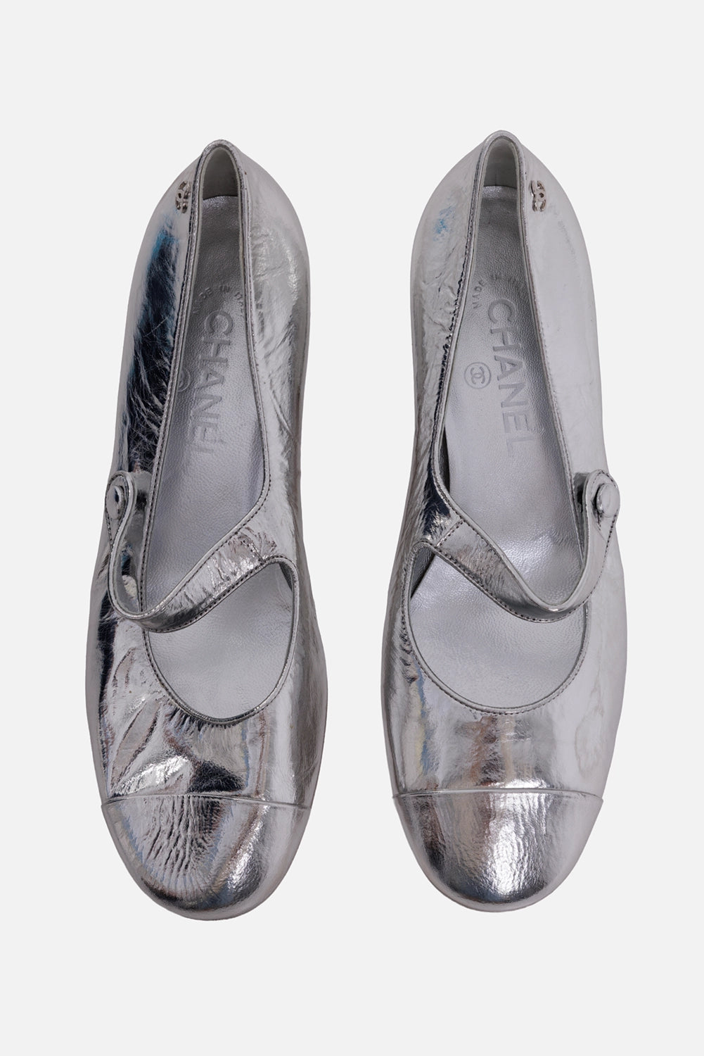 Chanel women's Mary Jane flats in silver, top view, branded leather insoles and button straps