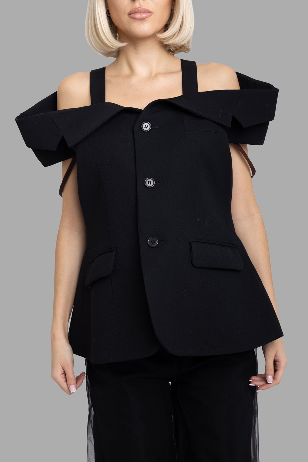 Noir Kei Ninomiya women's black off-shoulder wool blazer, front half-length view with strap shoulders and flap pockets
