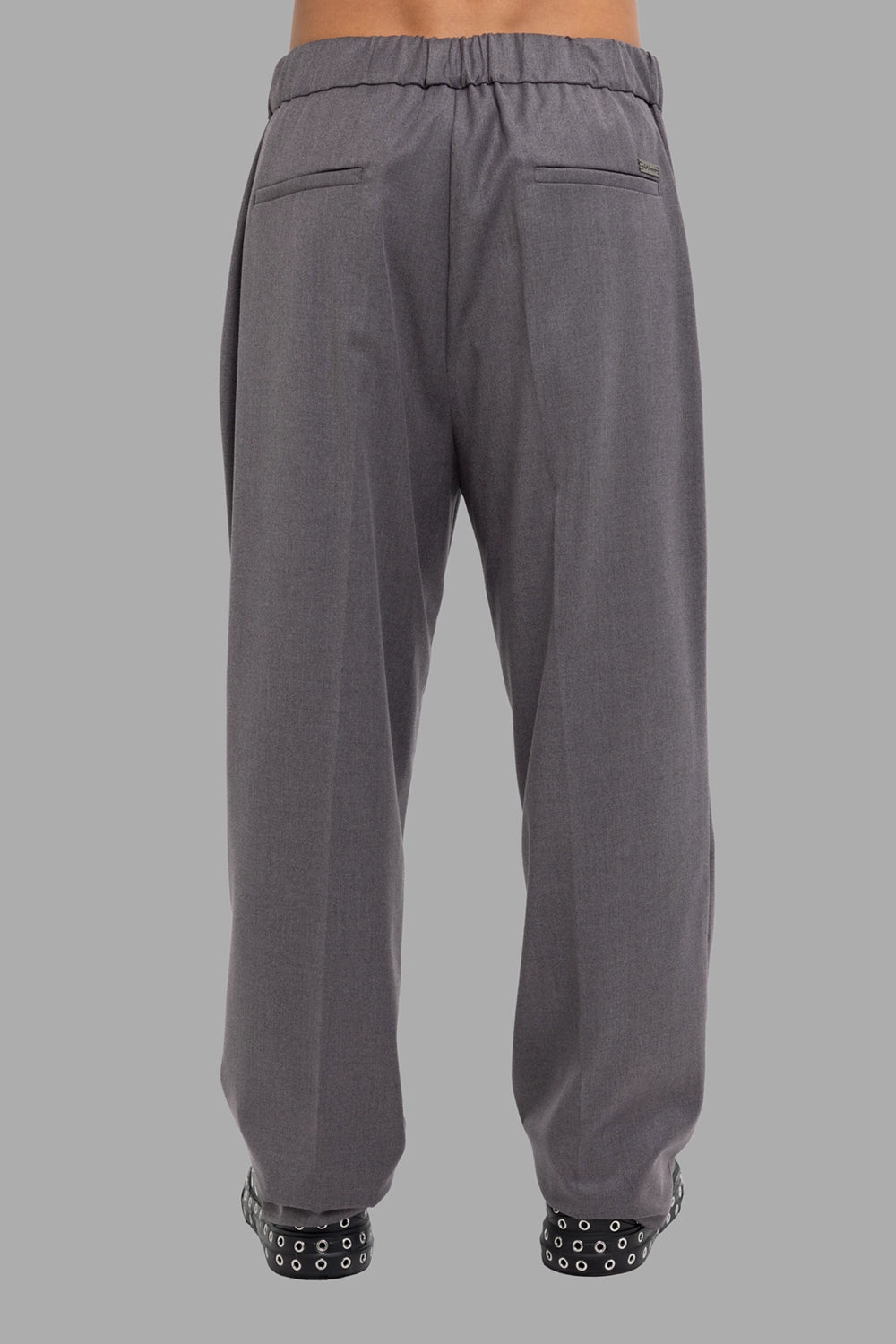 Gaëlle Paris men’s pleated trousers in grey, back view, elasticated waistband and welt pockets.