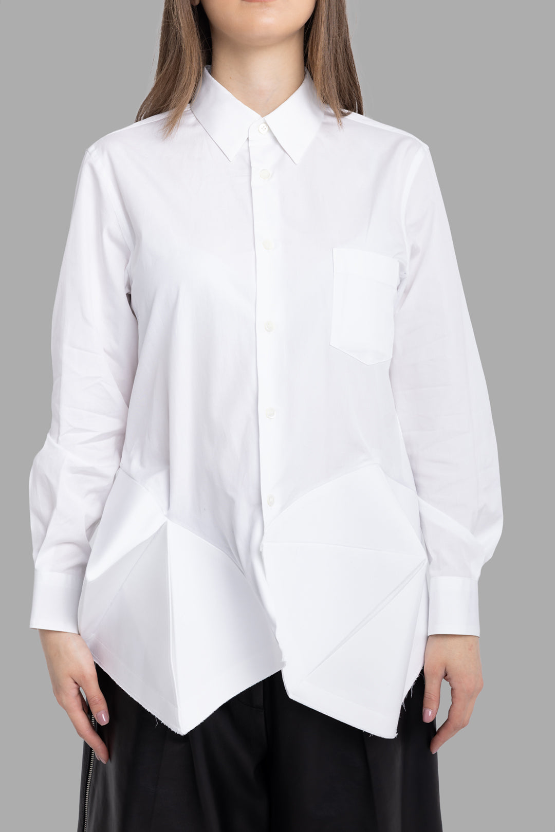 Comme des Garçons women's white ruffle bottom shirt, front view, pointed collar with chest pocket and sculptural hem panels.