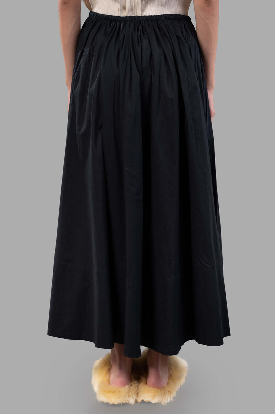 By Malene Birger Pheobes Cotton Skirt in black, highlighting its soft flow and high-waist detail from a side perspective on.