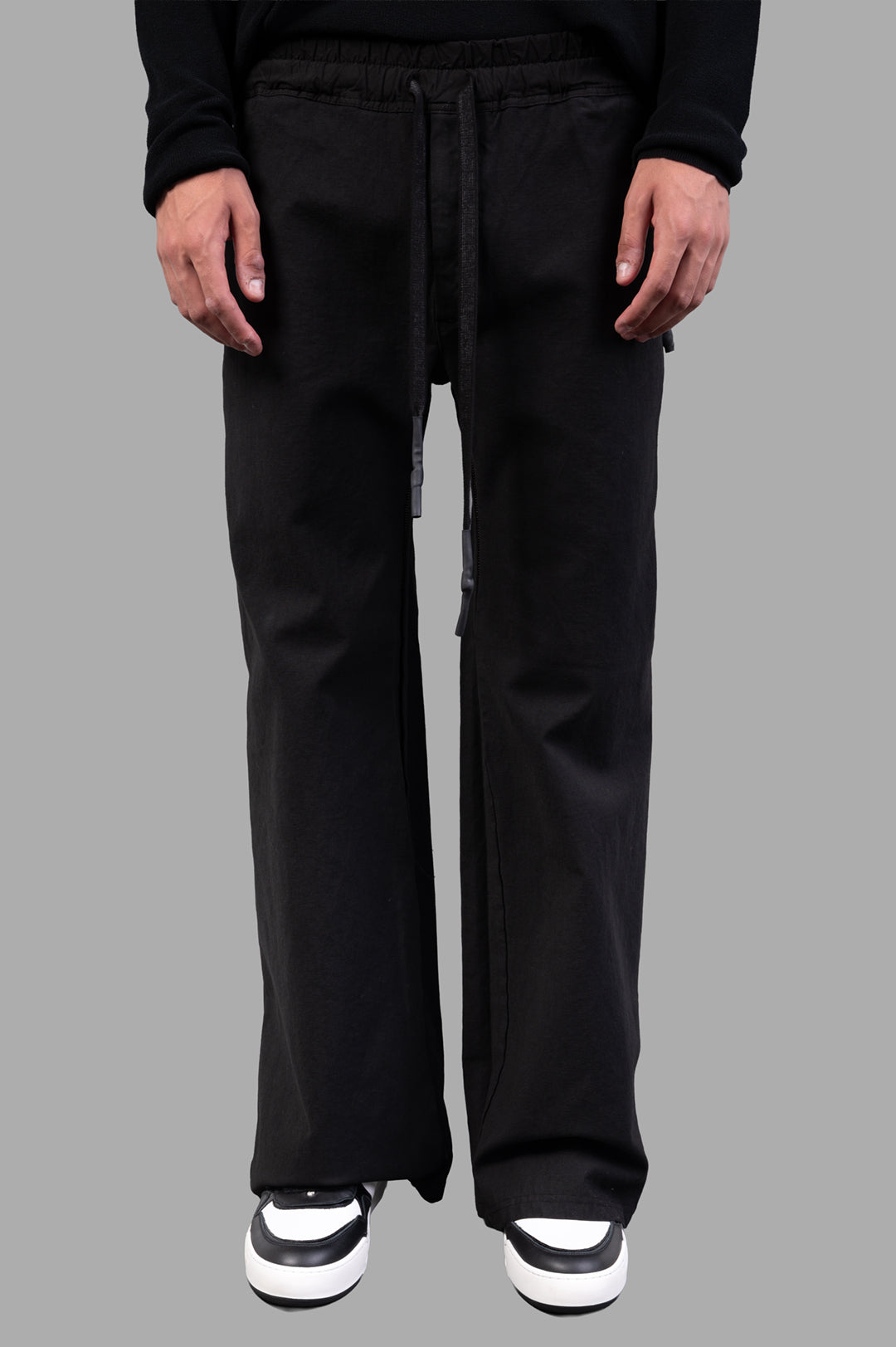 Isaac Sellam Drawstring Trousers in black, showcasing wide-legged silhouette and comfortable drawstring waist on model.