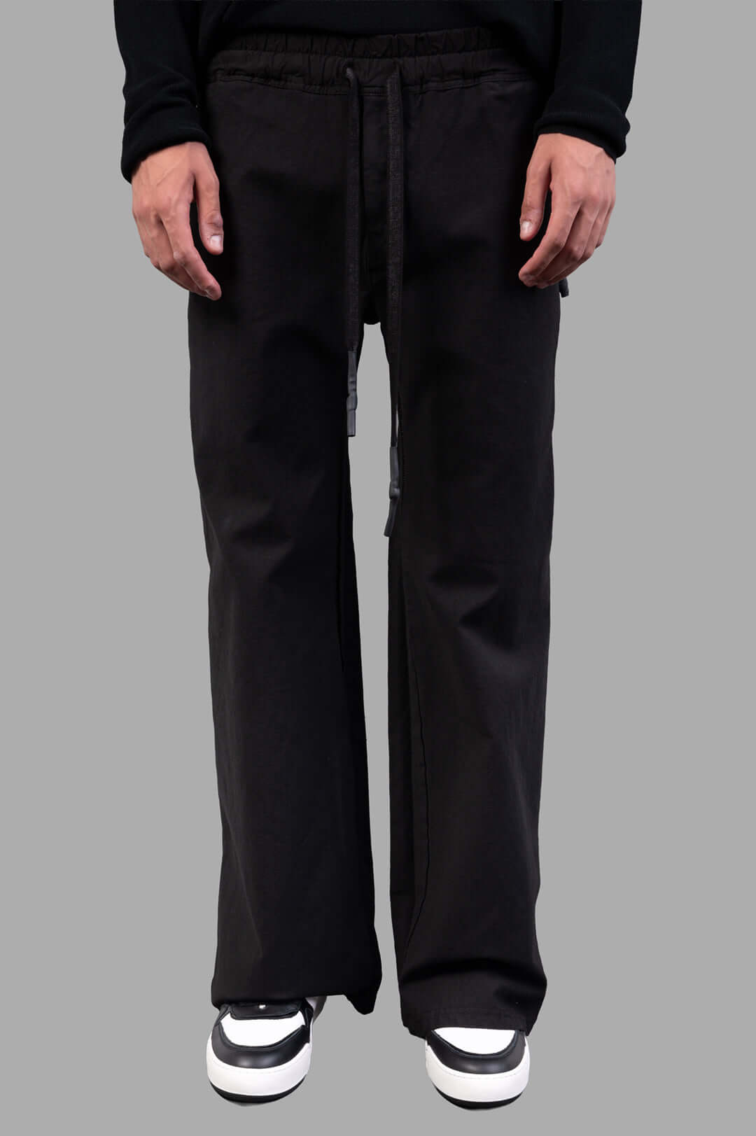 Isaac Sellam Drawstring Trousers in black, showcasing wide-legged silhouette and comfortable drawstring waist on model.
