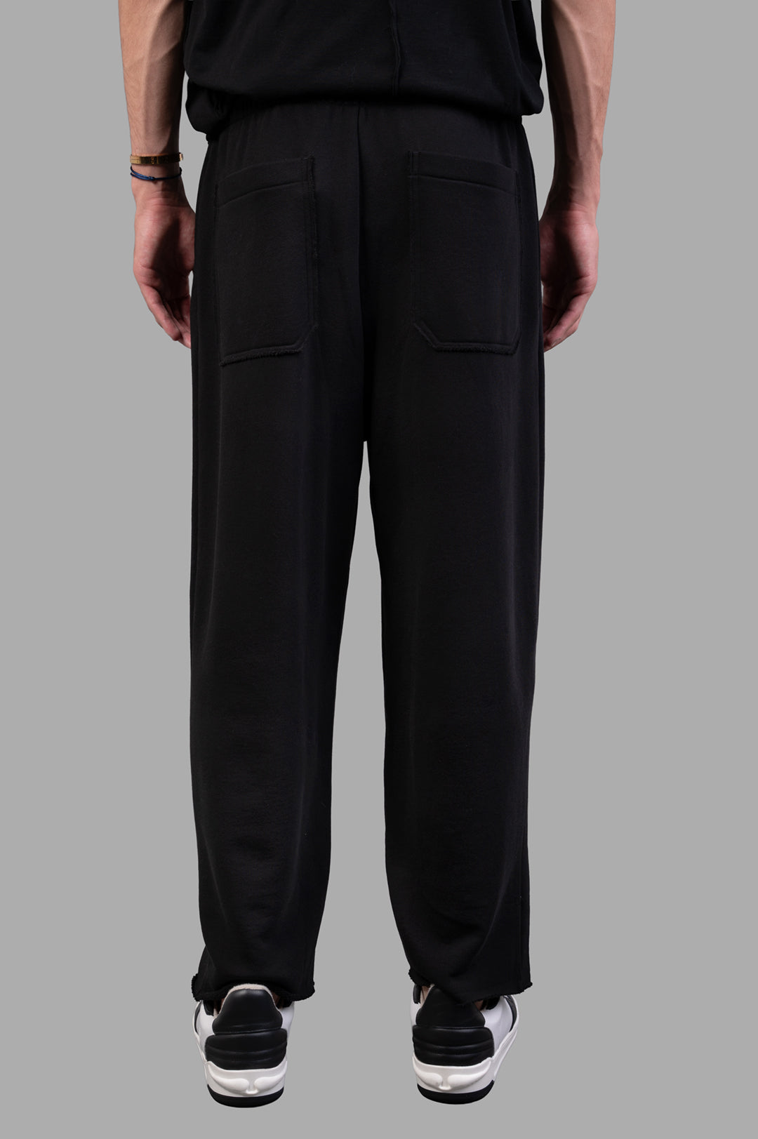 Helmut Lang Minimal Sweatpants in black, showcasing the back view with rubber logo patch and raw hem details.
