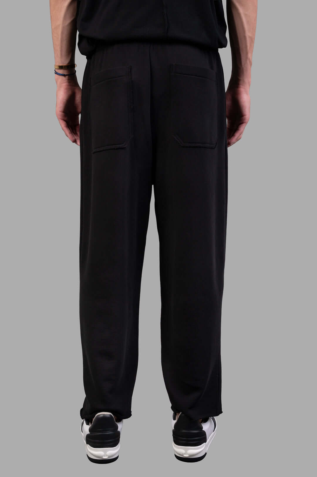 Helmut Lang Minimal Sweatpants in black, showcasing the back view with rubber logo patch and raw hem details.