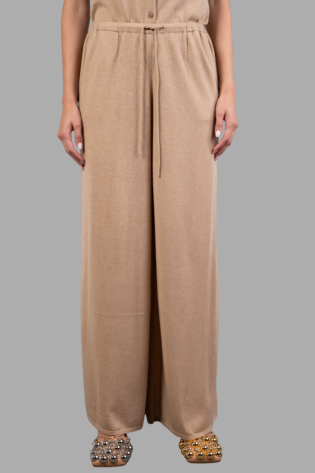 By Malene Birger Drawstring Trousers in beige, featuring a tie waist, wide legs, and side pockets, styled on a model.