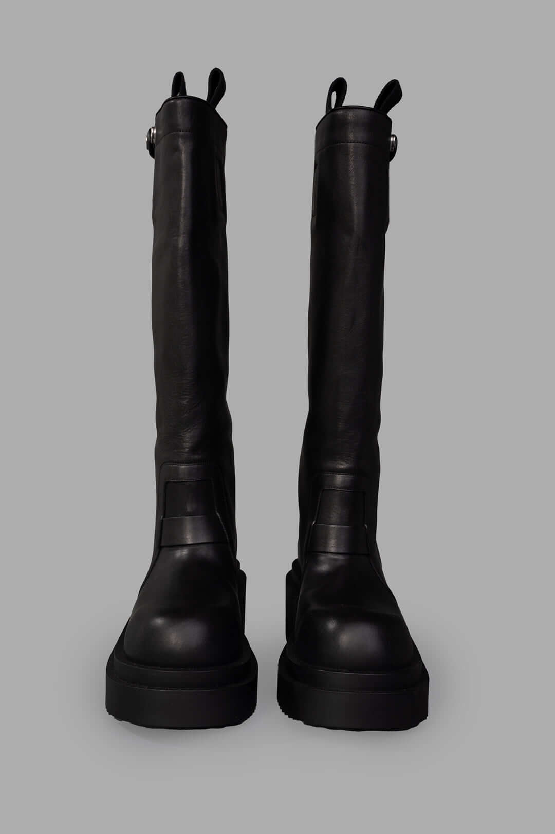 Rick Owens Bogun Knee-high Boots shown from the front, featuring sleek black leather and sturdy soles for a bold look.