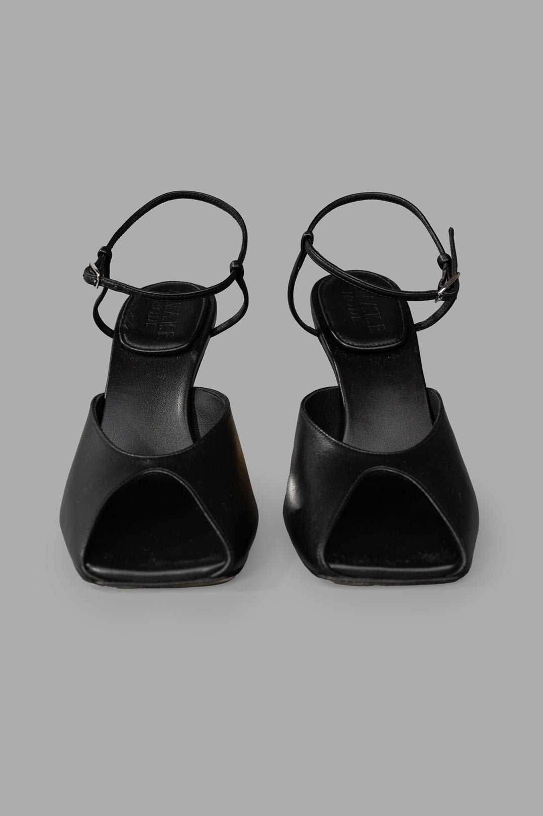 A.W.A.K.E. MODE Giustine Leather Sandals in black, showcasing sleek open-toe design and slim ankle straps from the front.