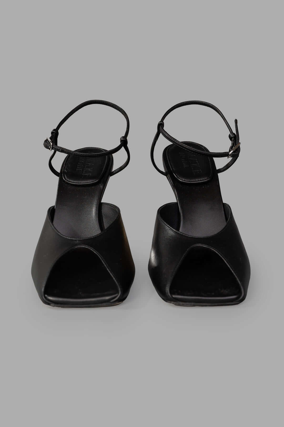 A.W.A.K.E. MODE Giustine Leather Sandals in black, showcasing sleek open-toe design and slim ankle straps from the front.