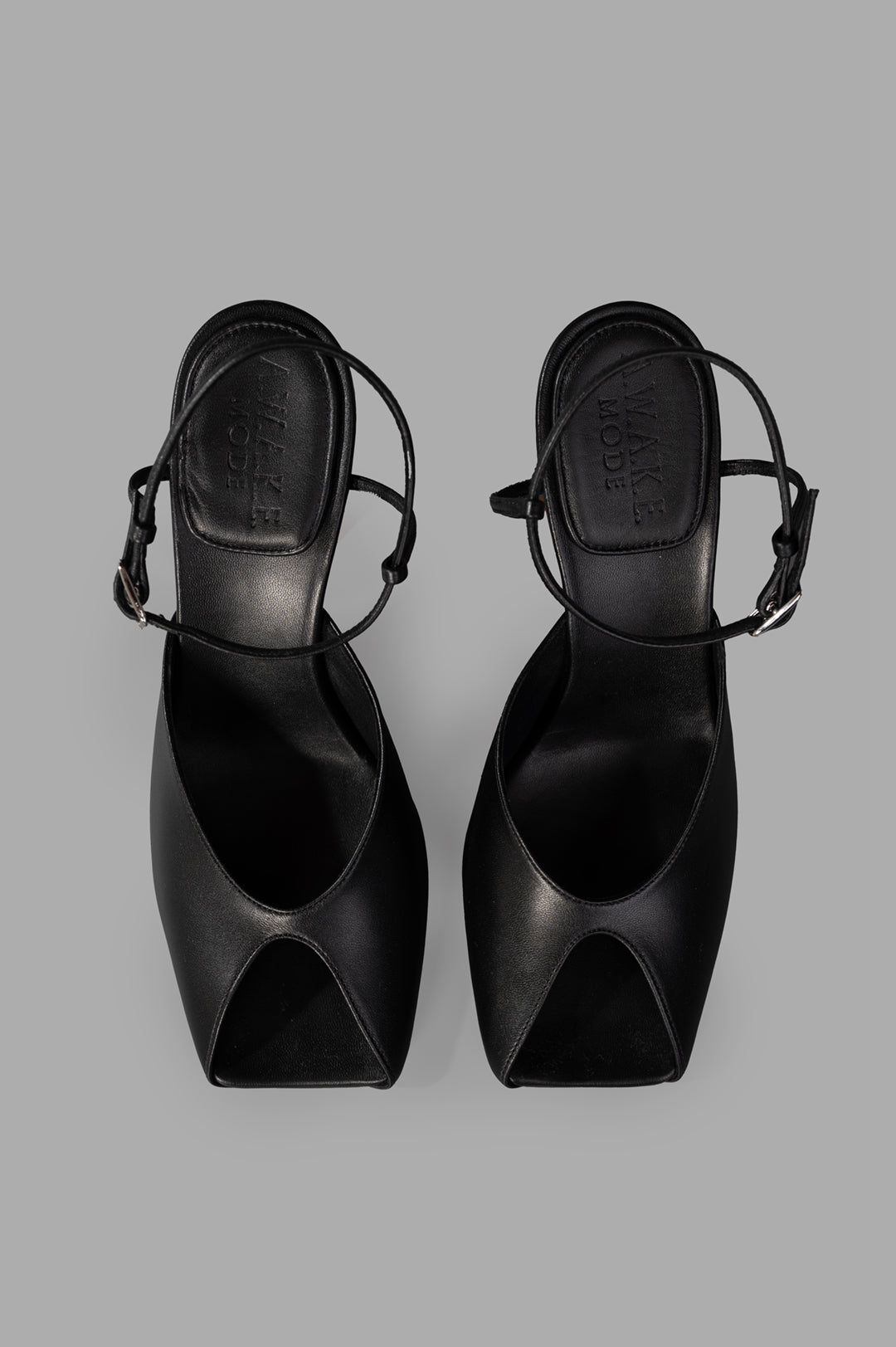 A.W.A.K.E. MODE Giustine Leather Sandals in black, showcasing a sleek open-toe design and slim ankle strap from above.