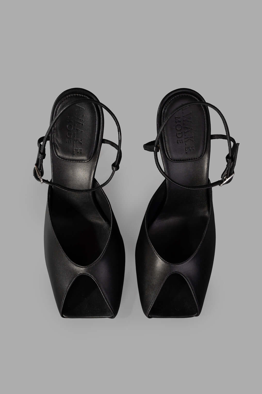A.W.A.K.E. MODE Giustine Leather Sandals in black, showcasing a sleek open-toe design and slim ankle strap from above.