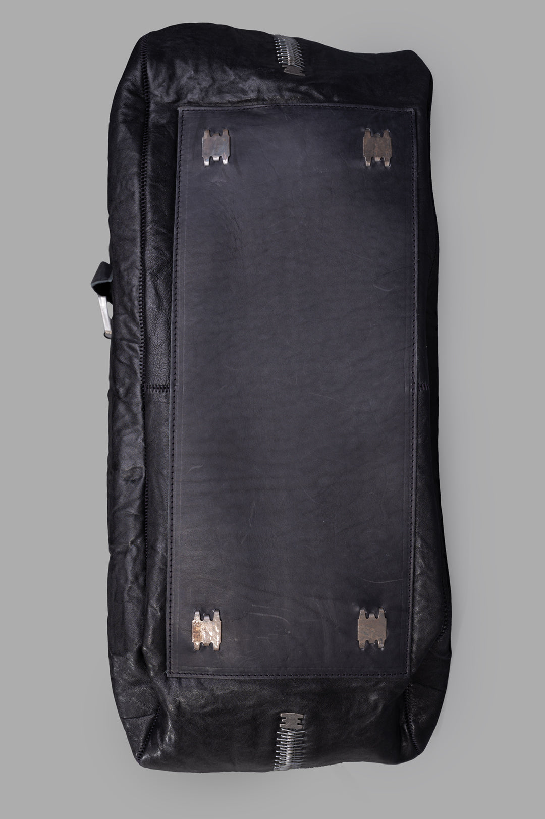 Isaac Sellam. Oversized Leather Bag showing the durable crinkled leather texture and unique metallic accents on the bottom.
