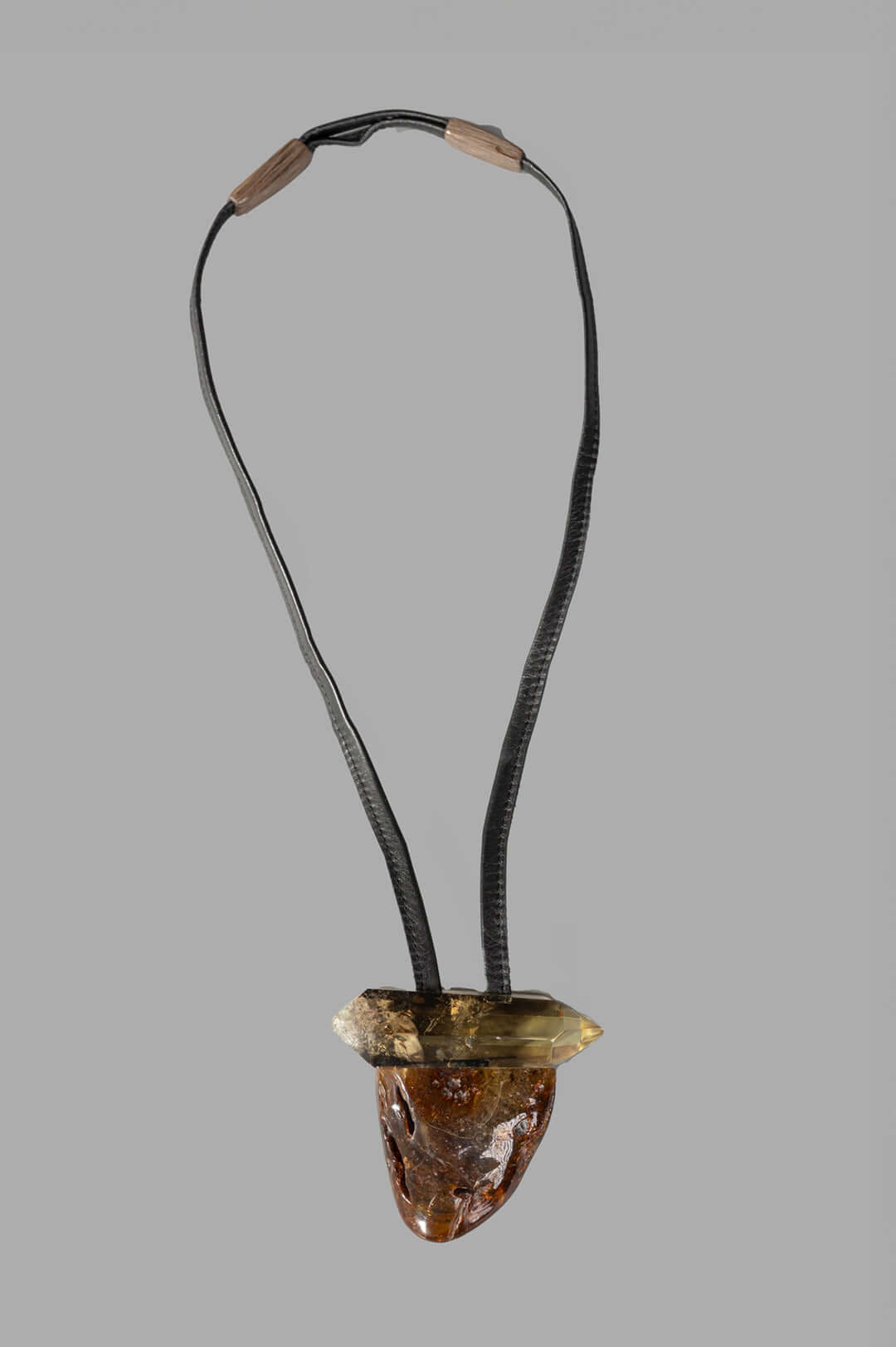 Monies Pendant Necklace features a large amber and citrine stone pendant on a black leather strap, showcasing front detail.