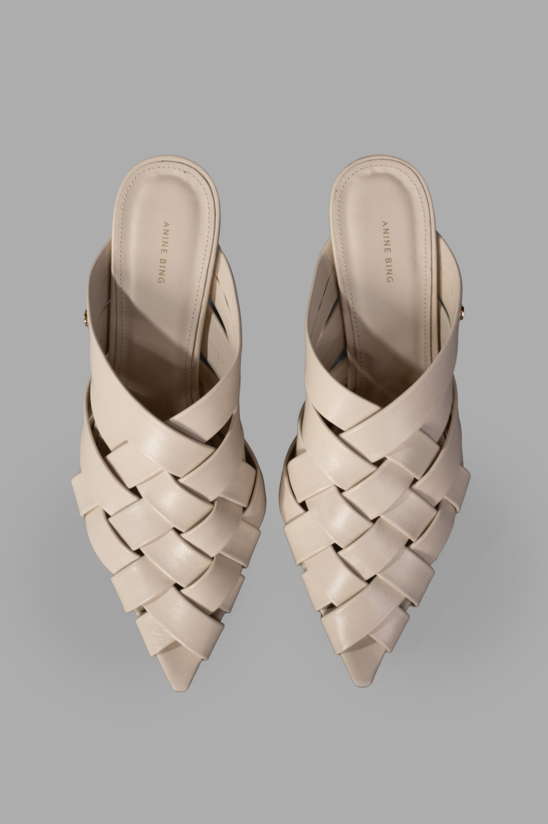 Anine Bing Eve Mules in bone, showcasing a woven design with smooth leather straps from a top view.