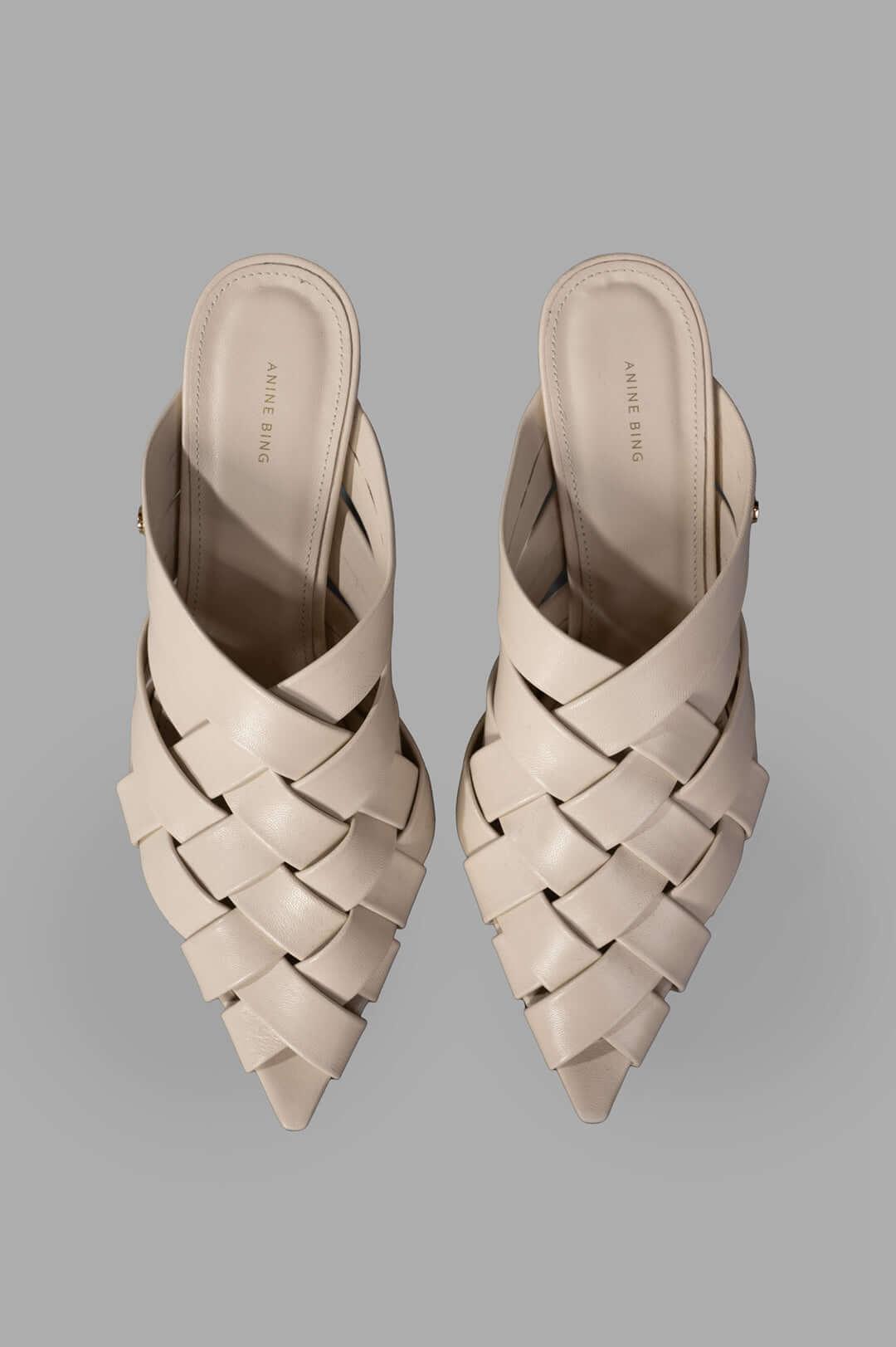 Anine Bing Eve Mules in bone, showcasing a woven design with smooth leather straps from a top view.