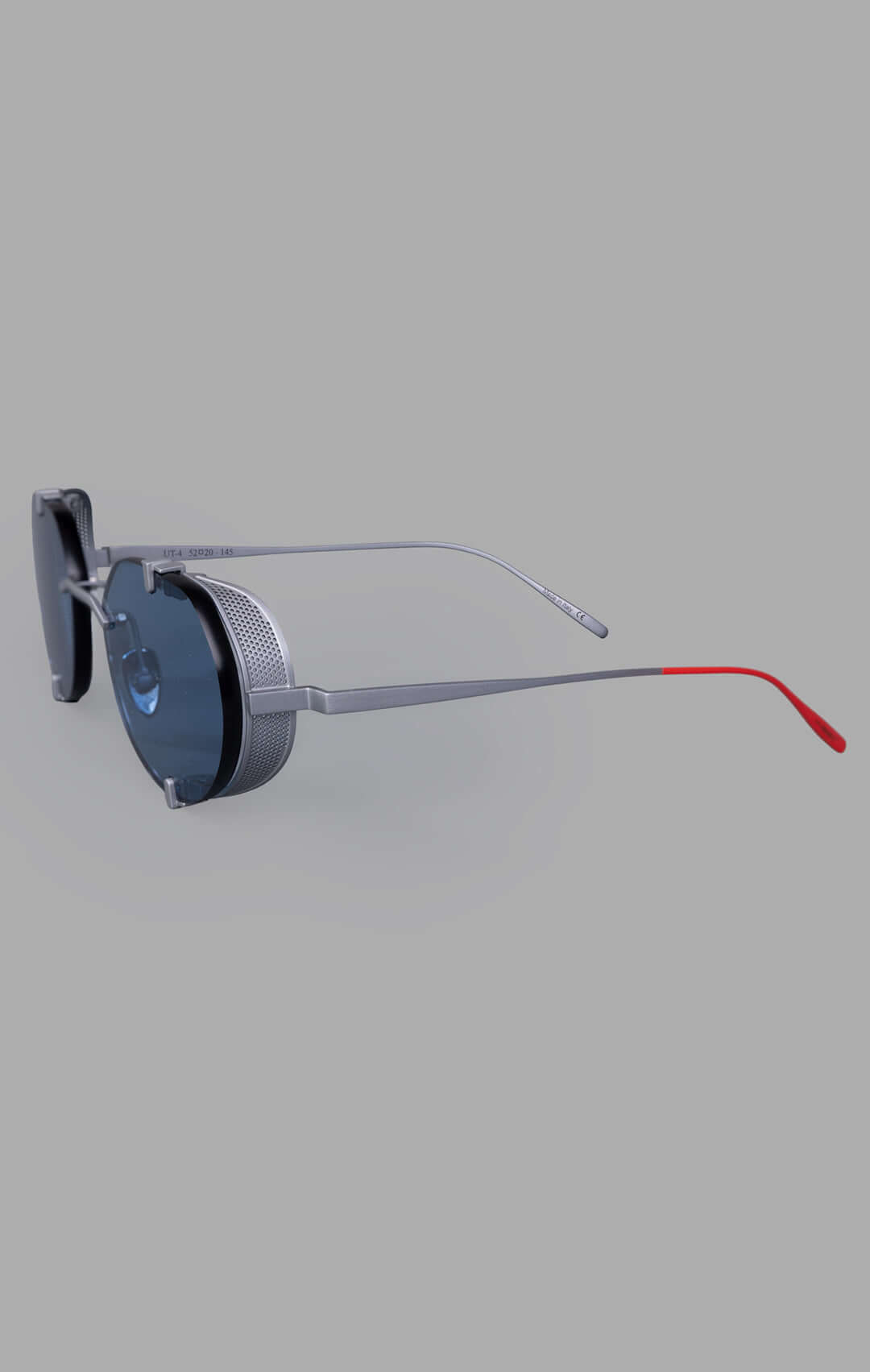 Vysen Eyewear The Uttar - UT4 showcases a side view of rimless titanium round frames with clear blue lenses and red accents.