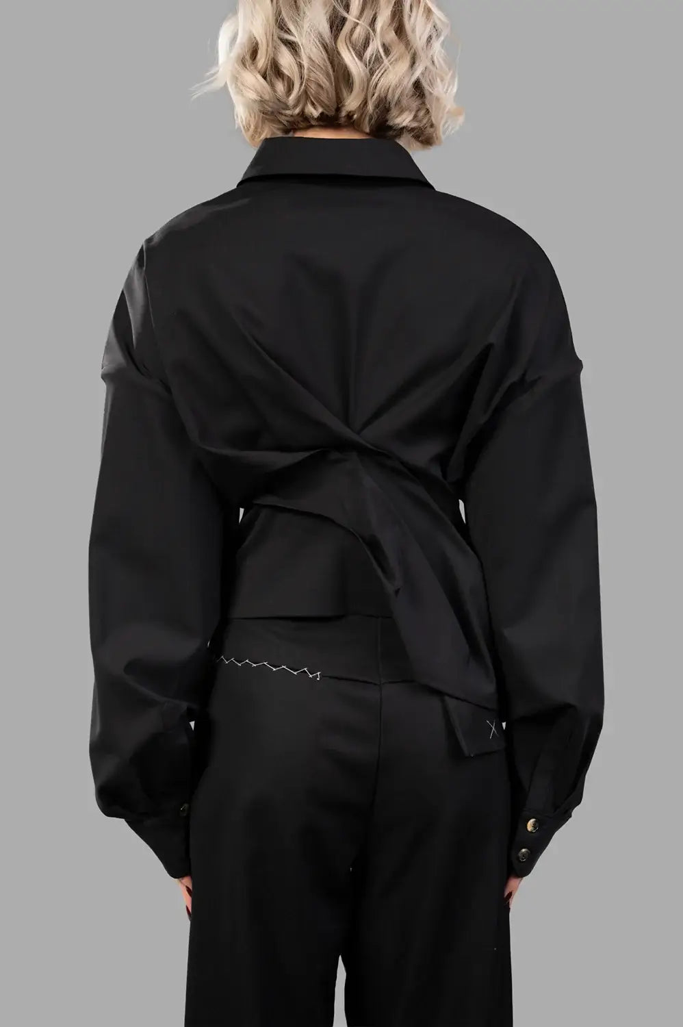 Back close-up of black twisted shirt showing wrapped panels and buttoned cuffs
