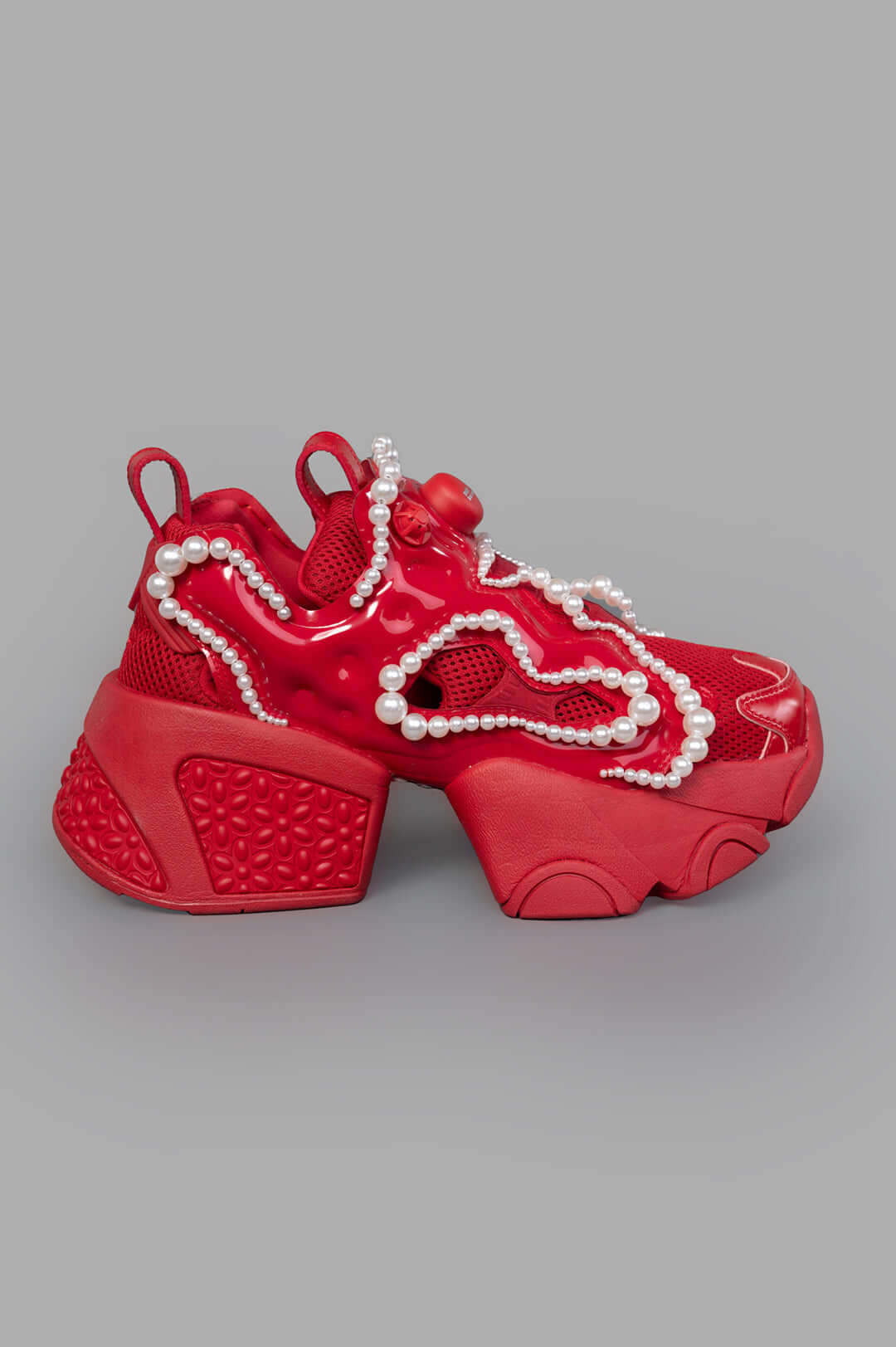 Noir Kei Ninomiya x Reebok red sneakers with pearl embellishments, side view. Features chunky sole and textured detailing.