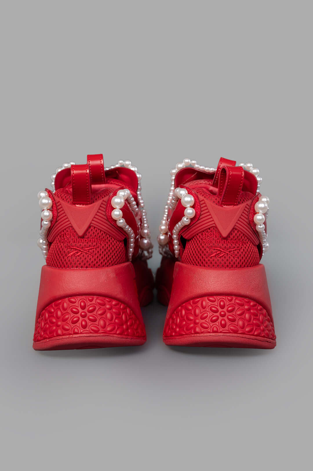 Noir Kei Ninomiya x Reebok red sneakers highlighting the vibrant front design adorned with striking pearl embellishments.