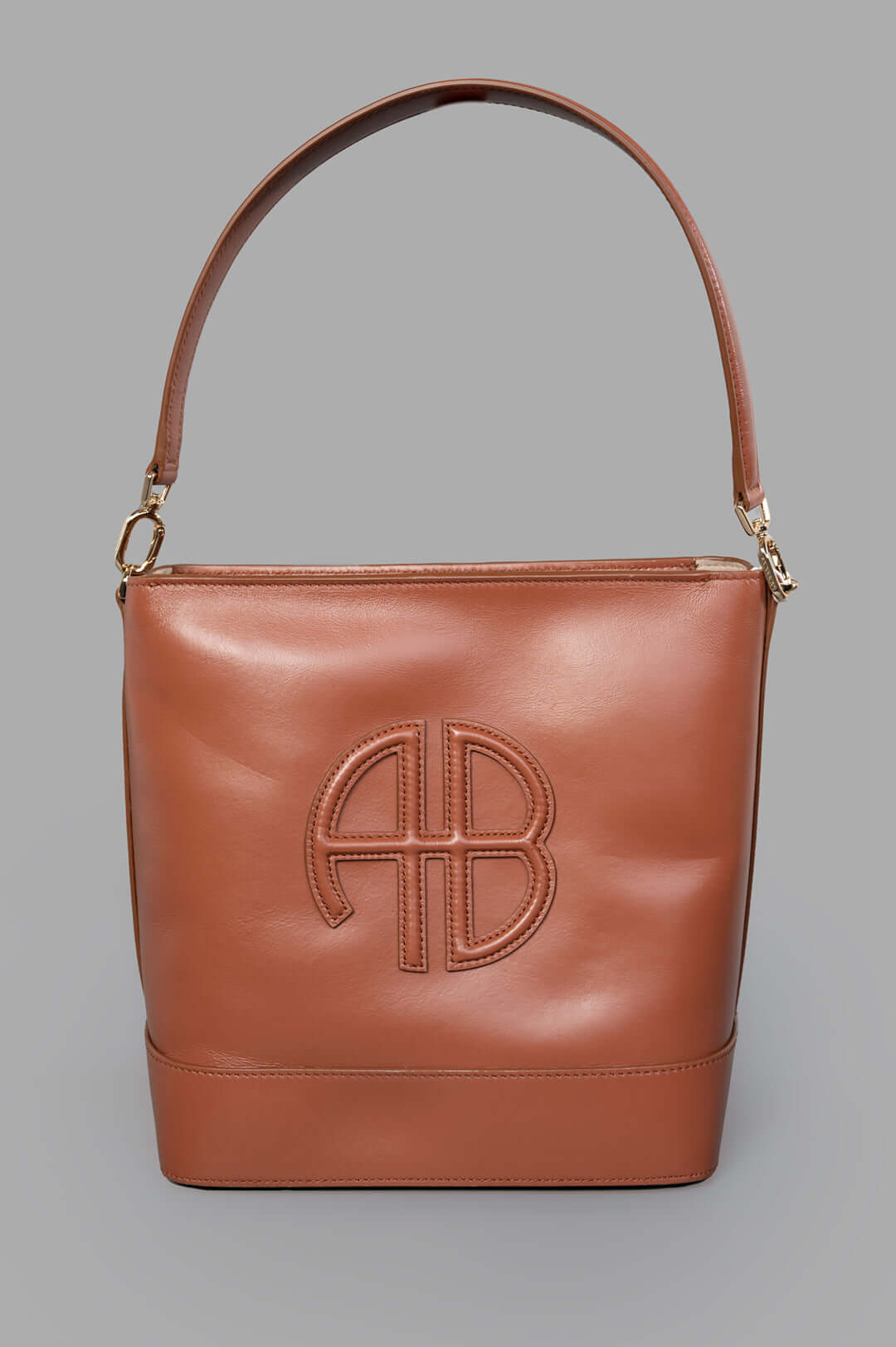 Anine Bing Lili Bucket Bag in cognac leather, front view with padded leather patch, gold hardware, and shoulder strap.