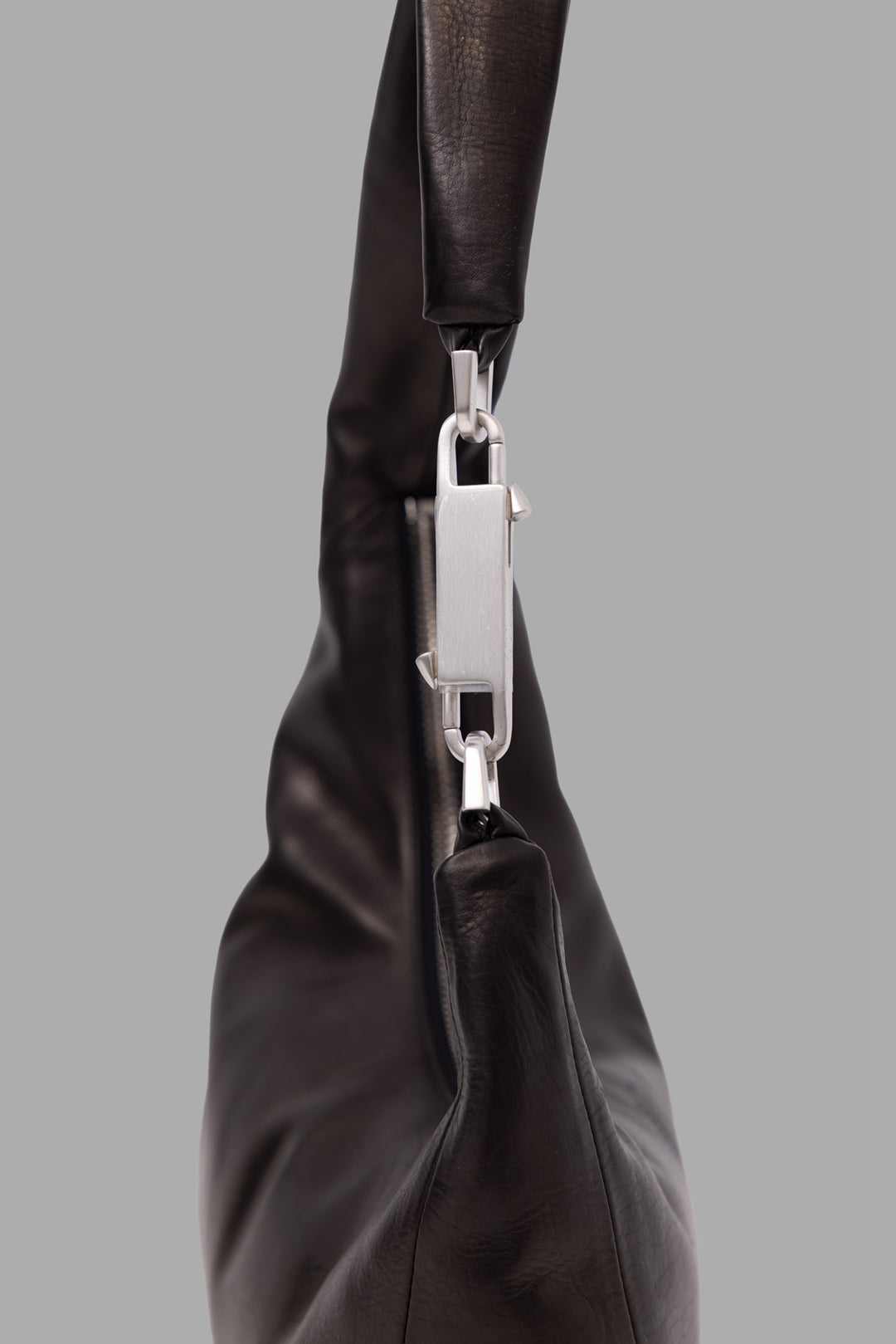 Rick Owens black small Gemini leather shoulder bag, close-up of silver carabiner hardware and leather shoulder strap.