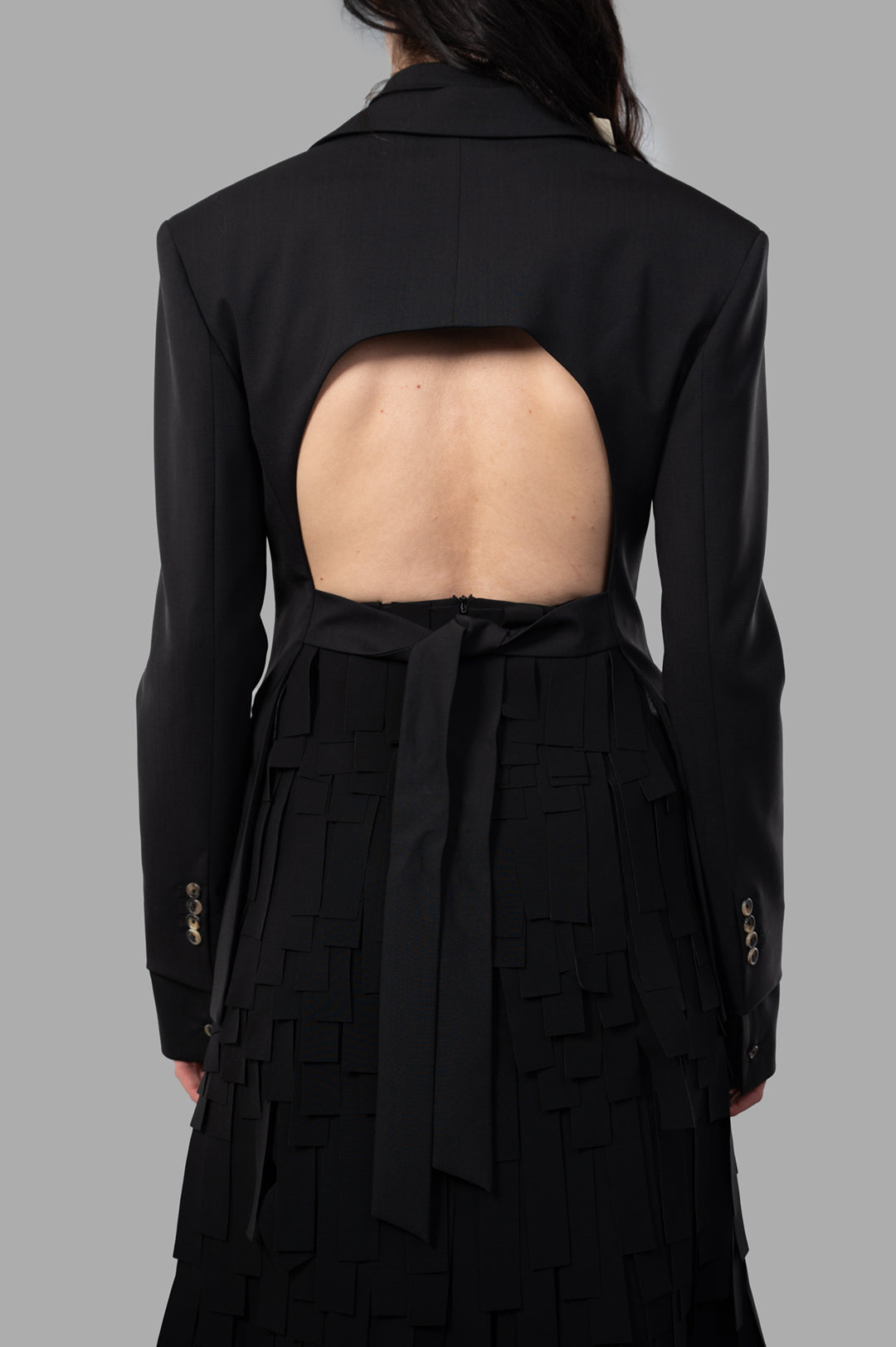 A.W.A.K.E. MODE Open-Back Blazer showcasing a unique back cut-out detail worn by a model, crafted from black wool blend.