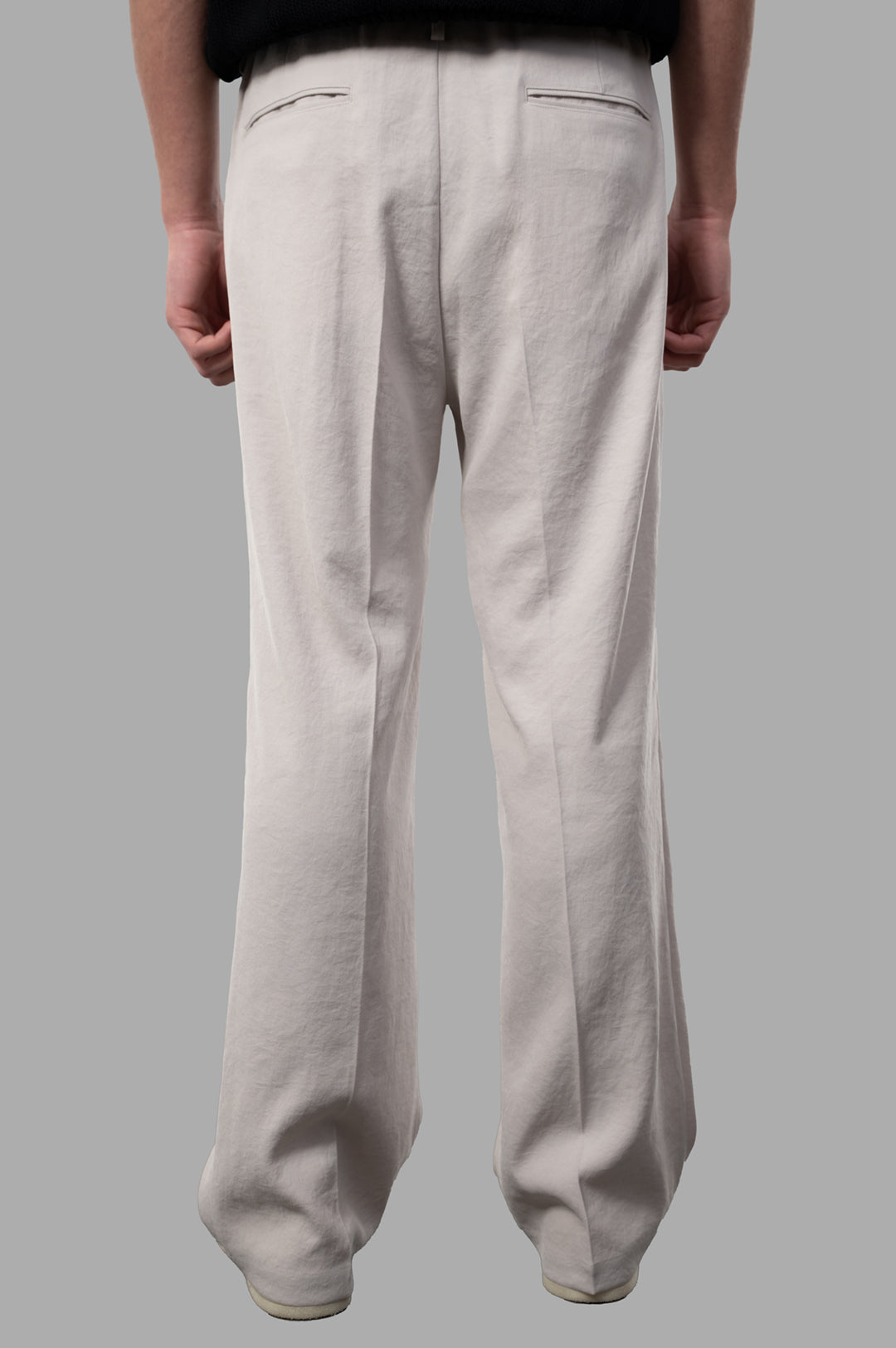Vein Pleated Trousers shown from behind, featuring relaxed fit, sleek pleats, and a beige 100% polyester material.
