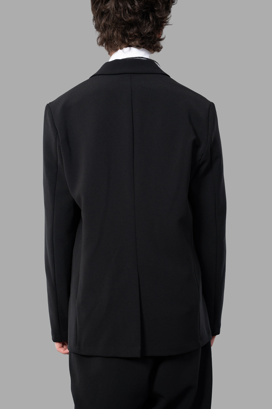 Attachment Single-breasted Blazer shown from the back, made of soft, stretchy black wool-like polyester fabric.