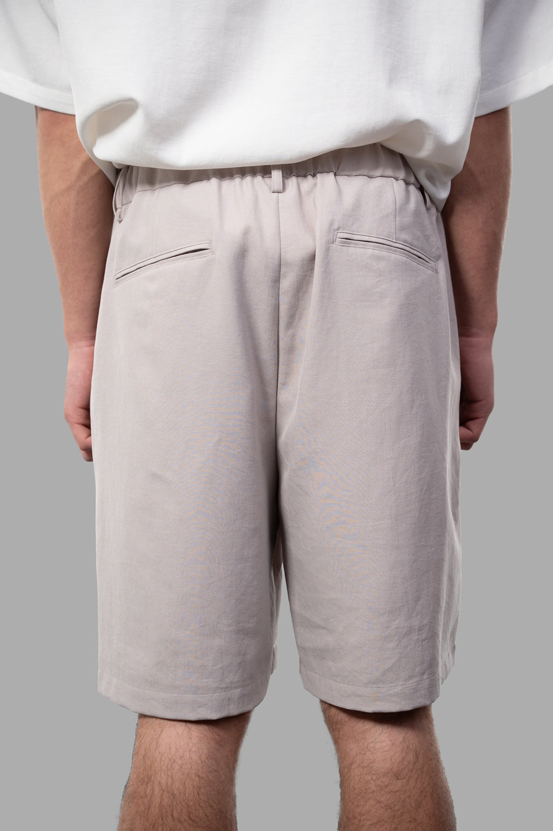 Attachment Twill Shorts in beige, featuring an elastic waistband and sleek back pockets, showcased from the back.