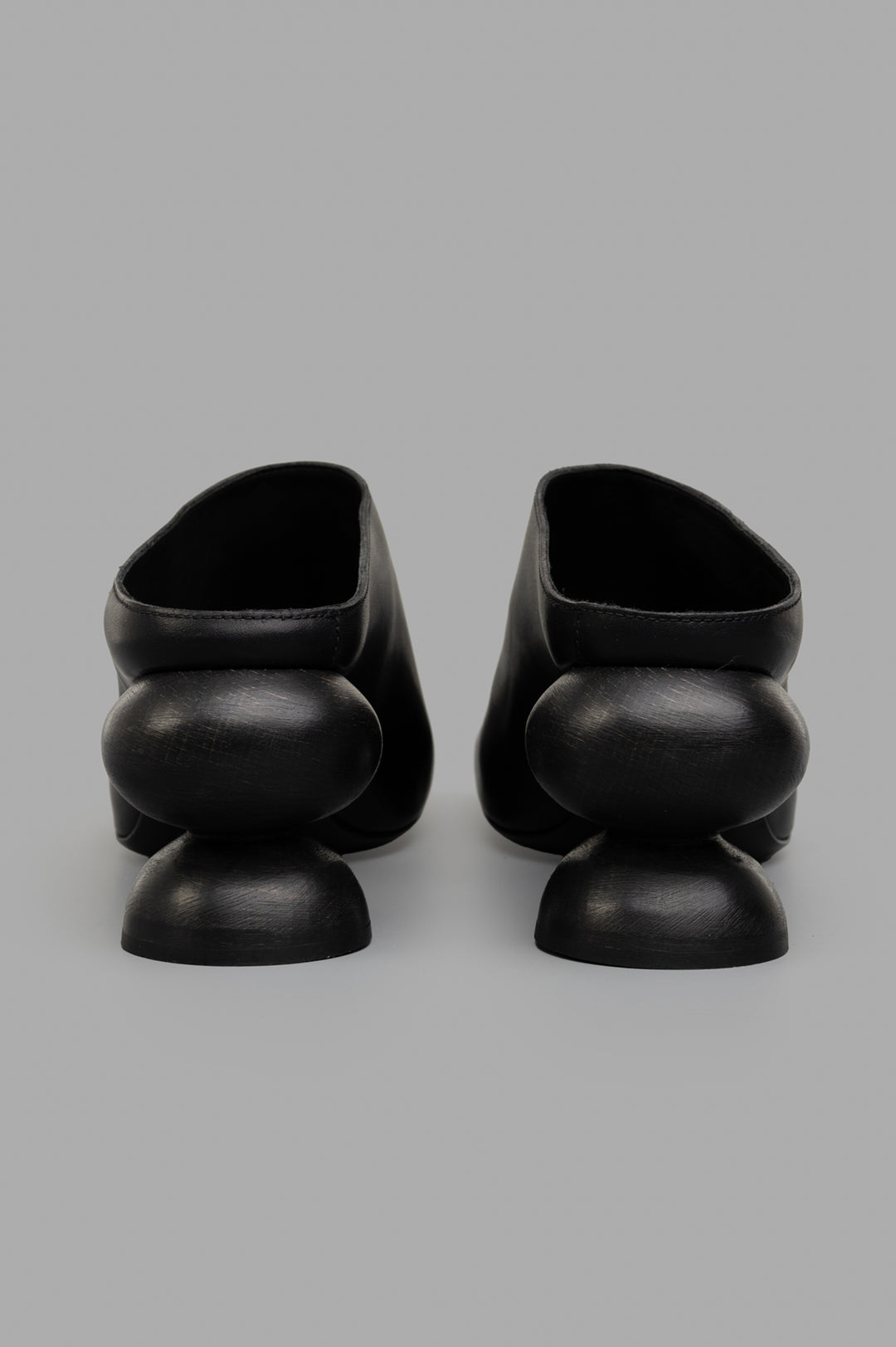 Uma Wang Stone Mules in Black, showcasing a close-up of the unique sculpted heel design, crafted from premium calf leather.