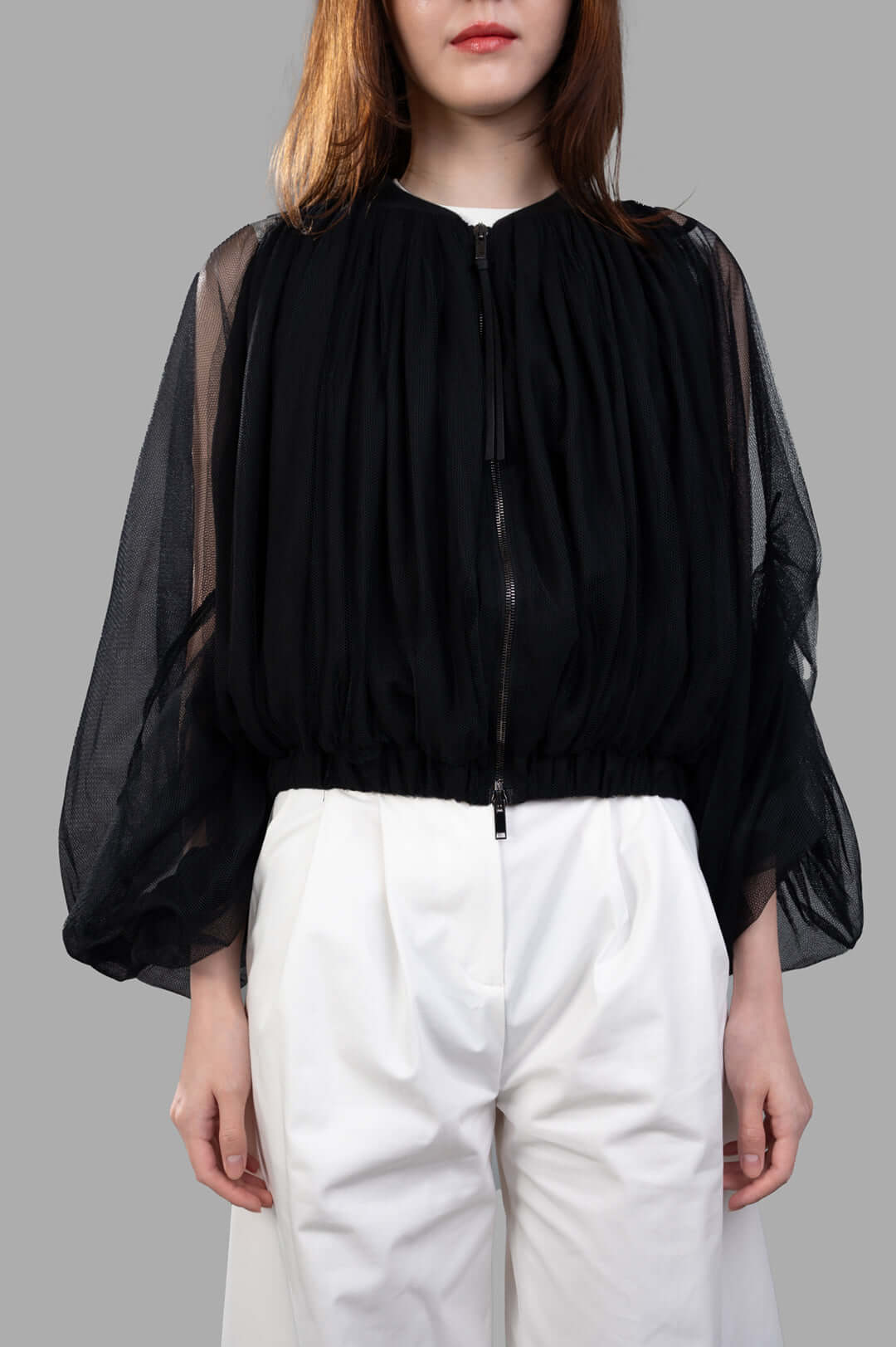 Giovanni Cavagna Mesh Bomber Jacket in black, featuring a relaxed fit with sheer sleeves, modeled with white trousers.