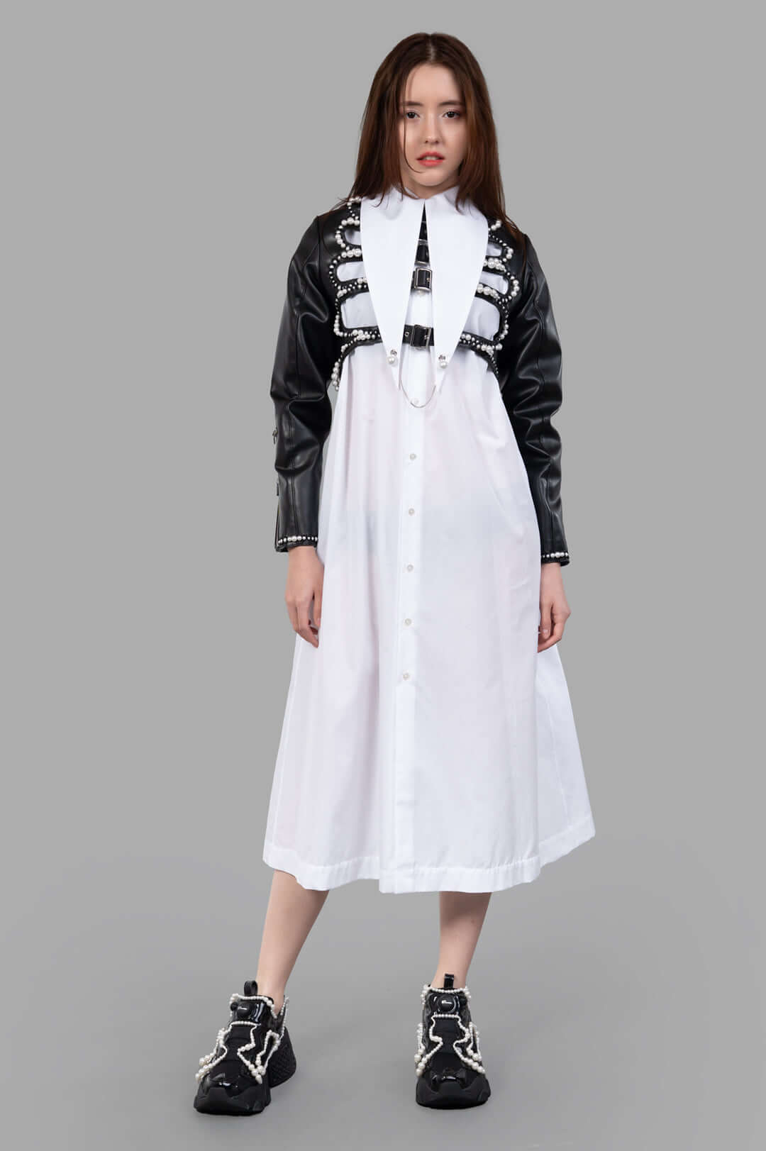 Noir Kei Ninomiya Pearl-Detailed Jacket on model, showcasing black faux leather with pearl accents and adjustable pin-buckle.