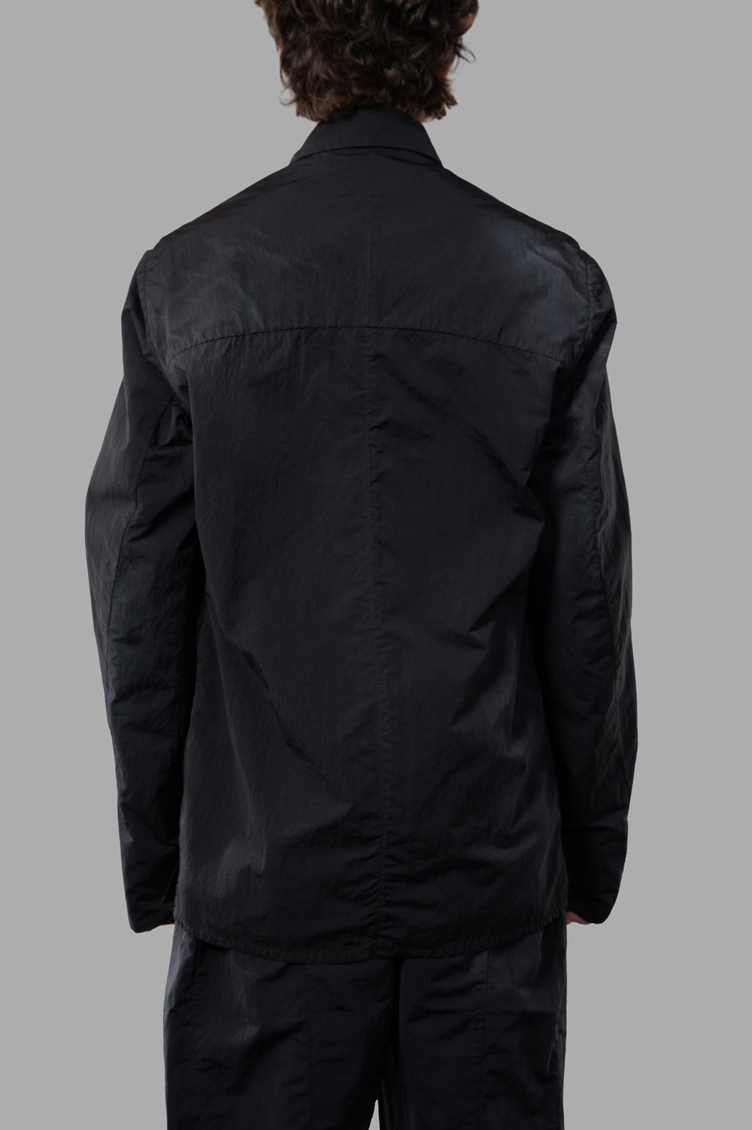 Marc Point Oversized Cargo Jacket viewed from the back, showcasing its sleek black nylon fabric and deconstructed design.